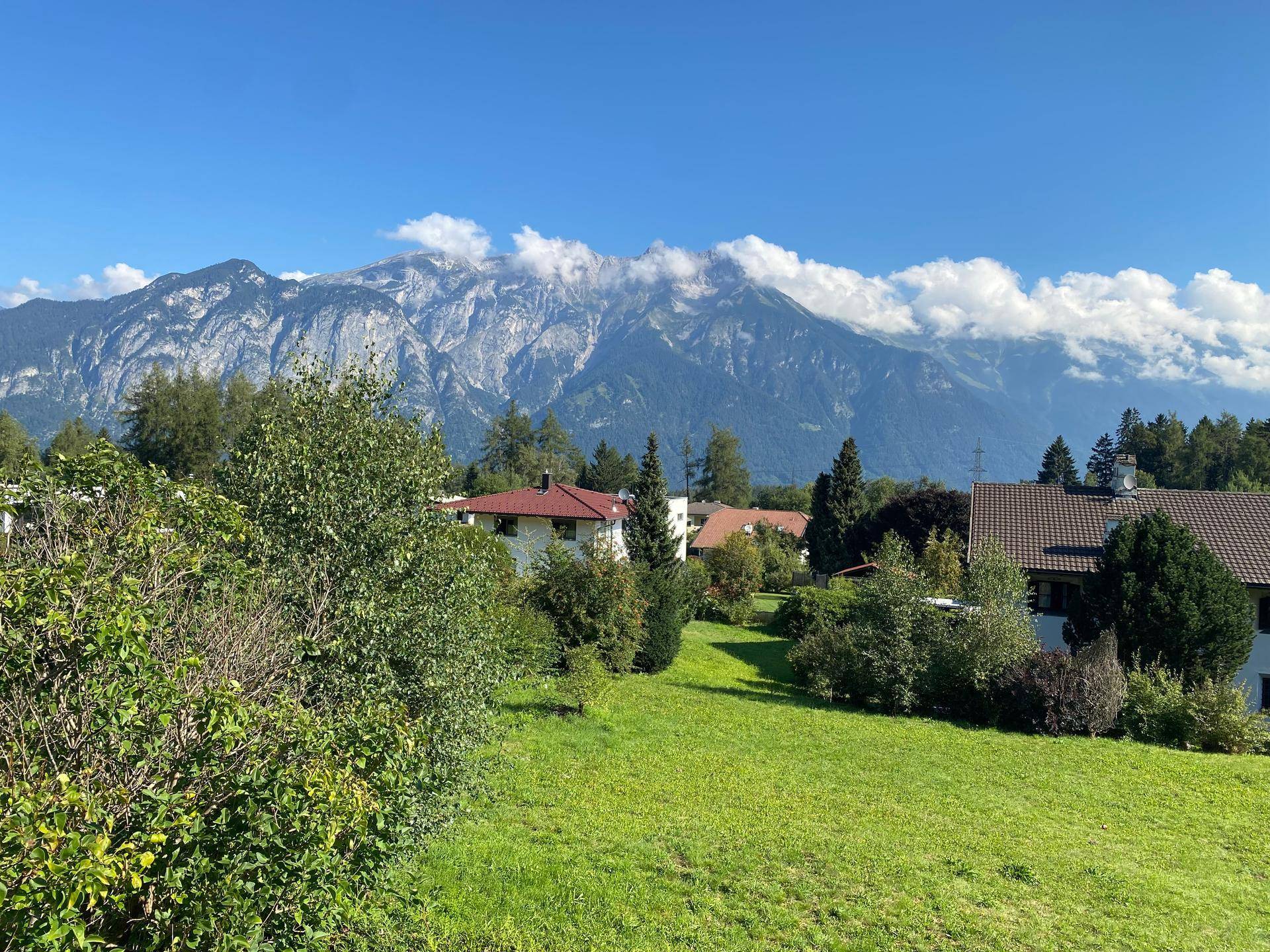 Panoramablick auf die umliegende Berglandschaft und die Wohngegend mit viel Grün.