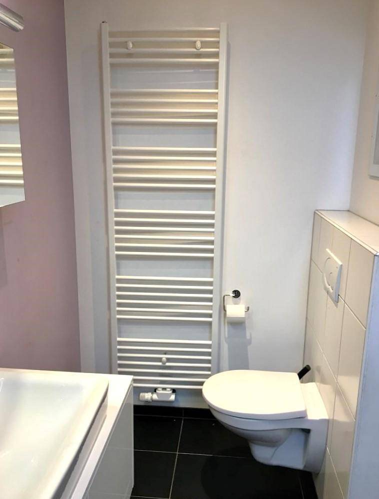 Modernes Gäste-WC mit Wand-WC, Waschbecken und beheiztem Handtuchhalter.