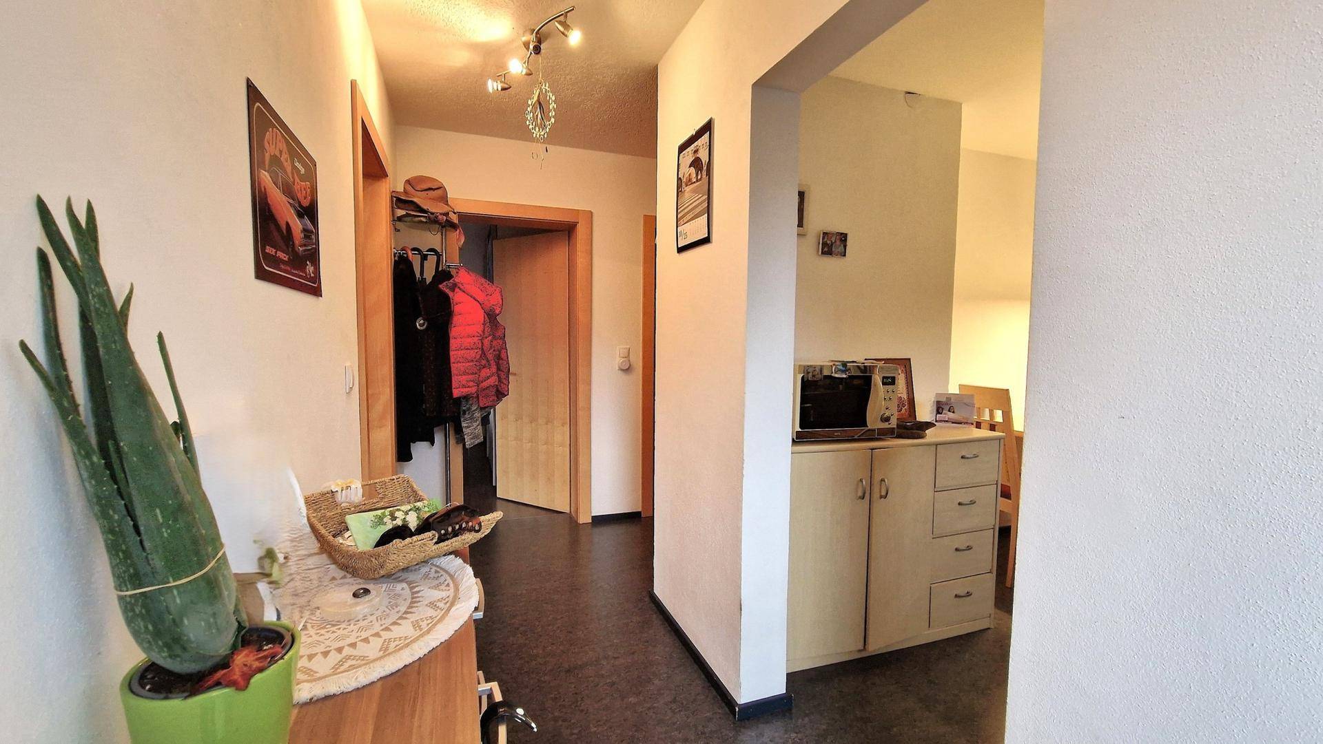 Geräumiger Flur mit Garderobe und Durchgang zu weiteren Räumen, hell beleuchtet.
