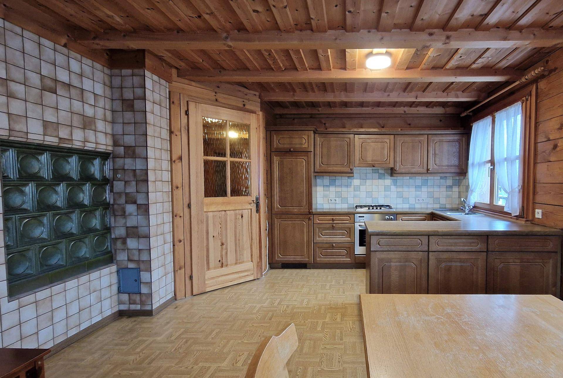 Traditionelle Holzküche mit Kachelofen, Holzschränken und Essbereich.