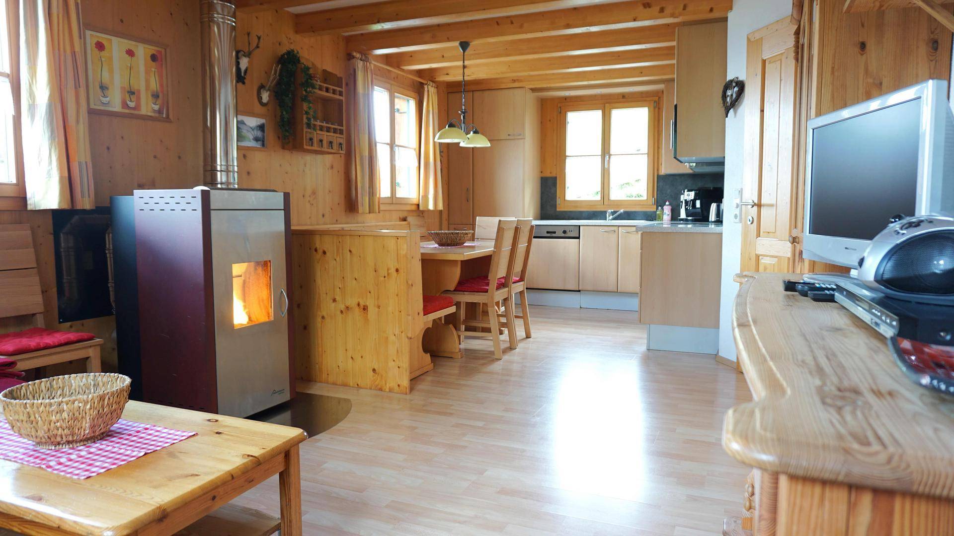 Offener Wohnbereich mit Holzboden, Kaminofen und integrierter Küche im Landhausstil.