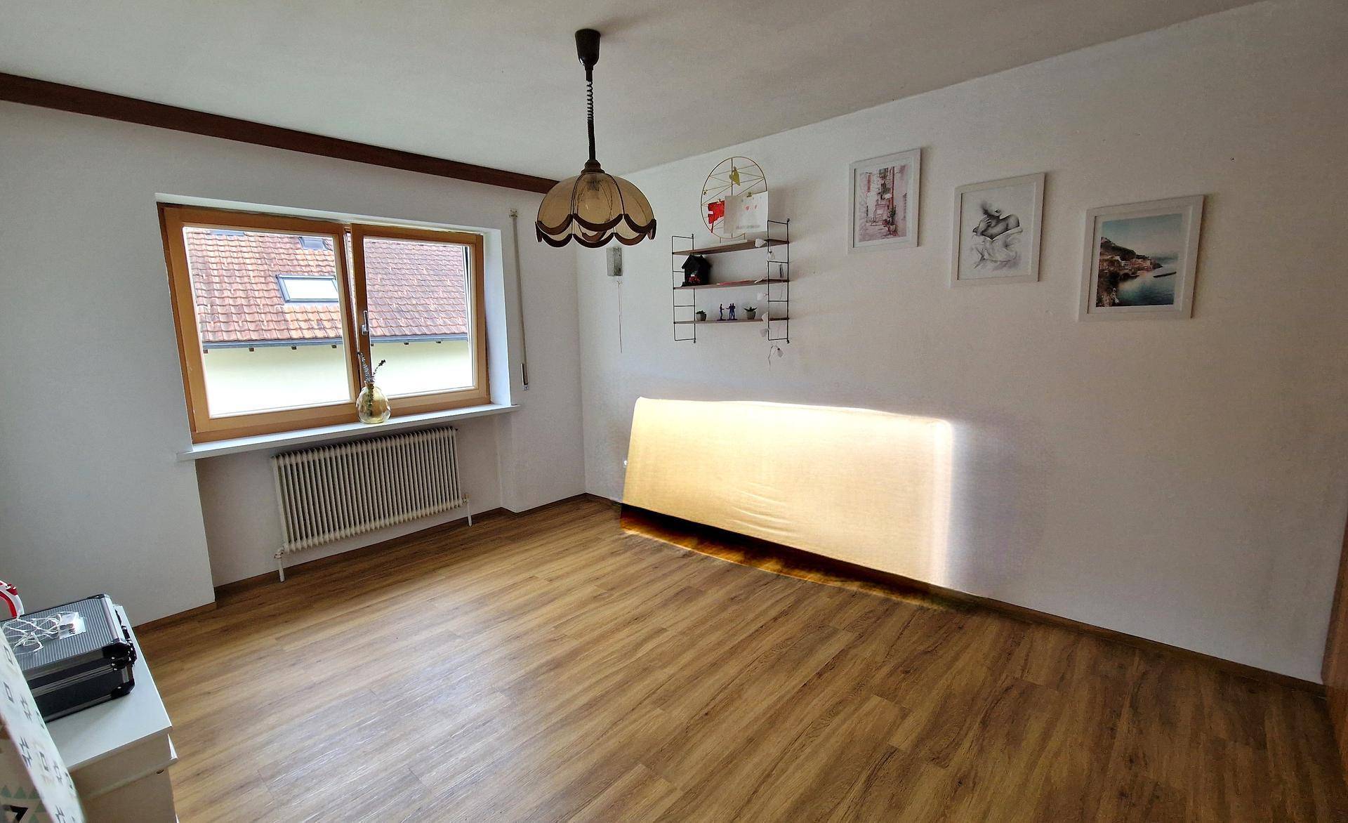 Geräumiges Schlafzimmer mit Laminatboden, großem Fenster und viel Tageslicht.