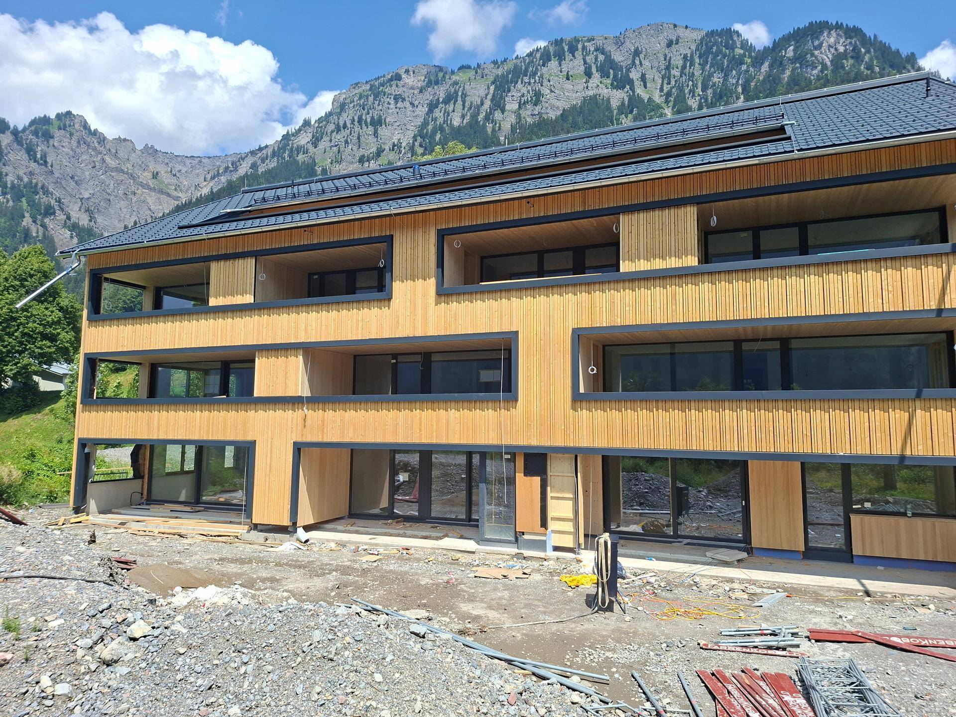 Detailansicht der modernen Holzfassade mit großzügigen Fensterflächen und Bergblick.