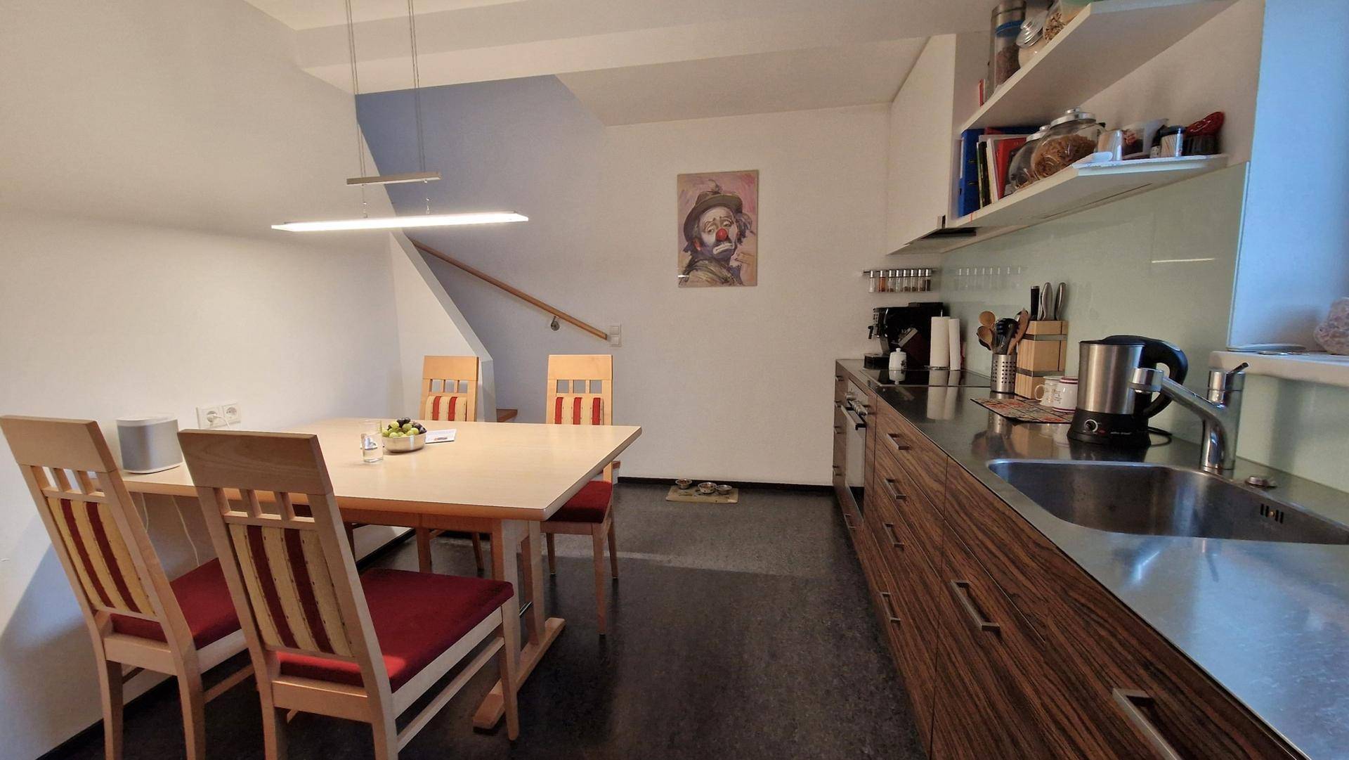 Moderne Küche mit dunkler Arbeitsplatte und Essbereich, offen gestaltet mit Treppenaufgang.