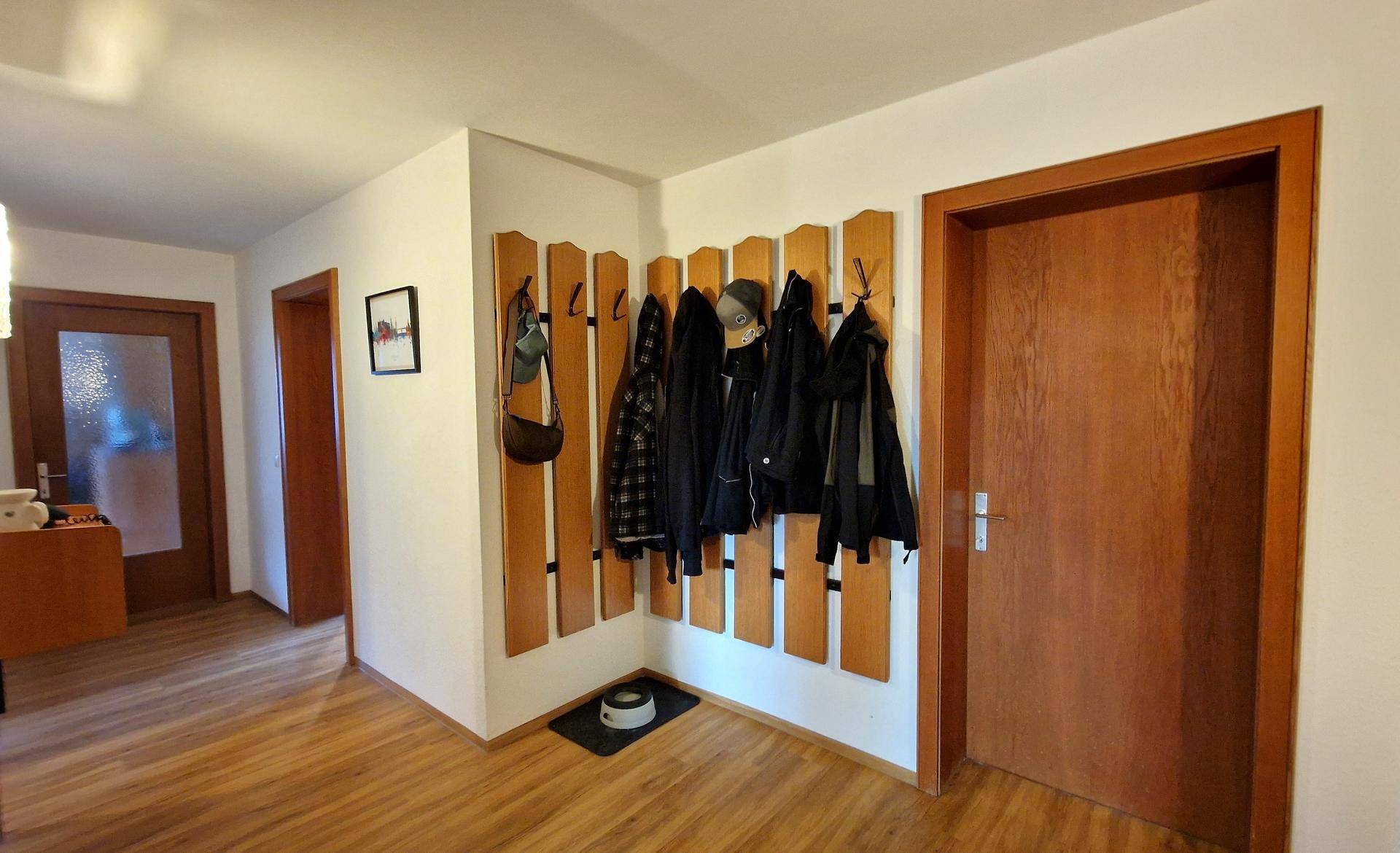 Flur mit praktischer Garderobe aus Holz und warmem Holzfußboden, gut gepflegt.