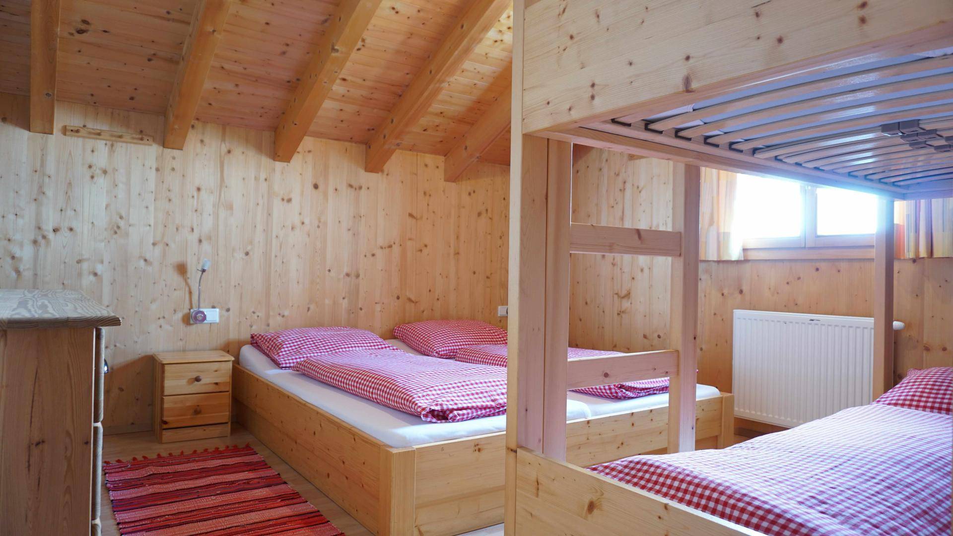 Schlafzimmer mit Holzwänden, Dachschräge und gemütlichen Betten im Landhausstil.