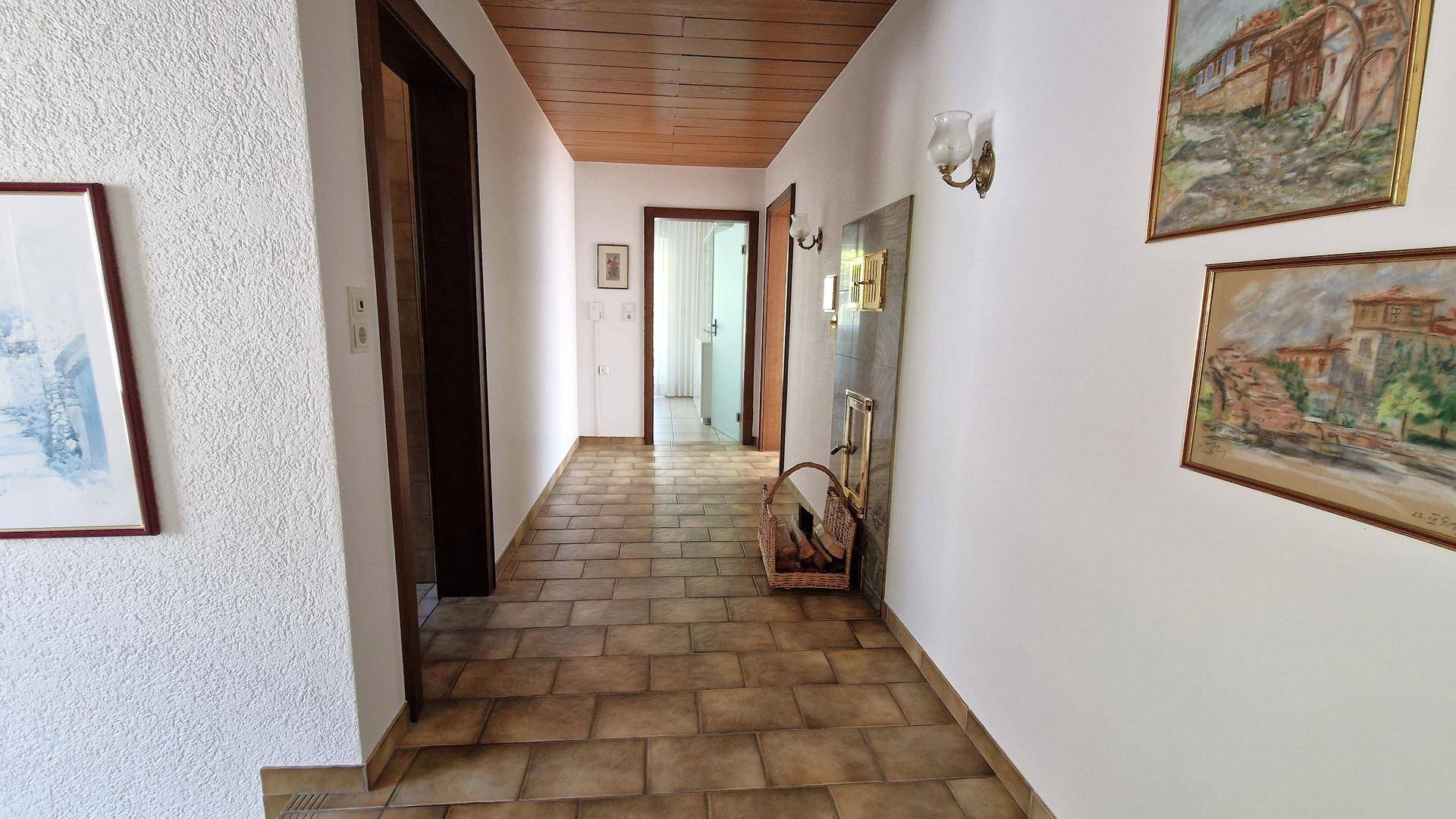 Geräumiger Flur mit Fliesenboden, Holzdecke und Zugang zu verschiedenen Zimmern.