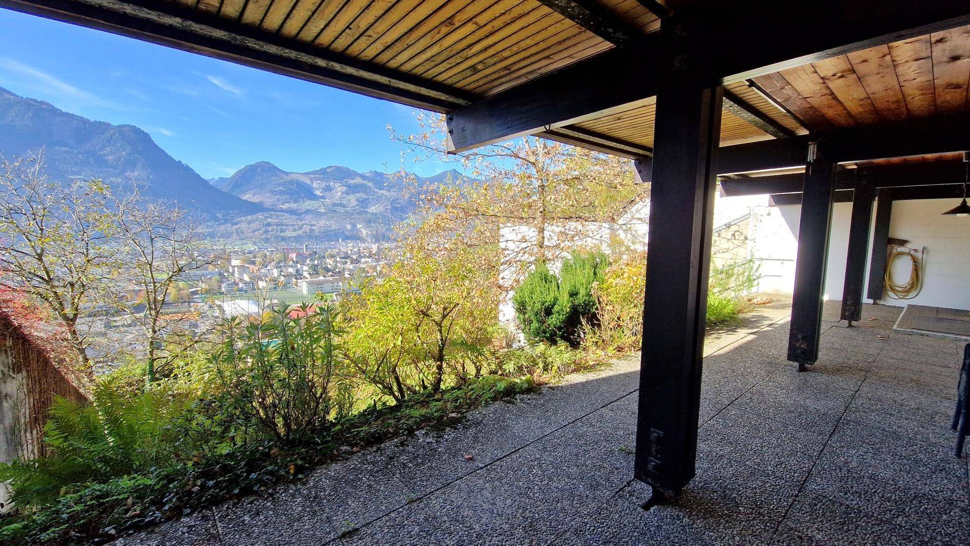 Überdachte Terrasse mit weitem Blick auf die Stadt und die umliegenden Berge.