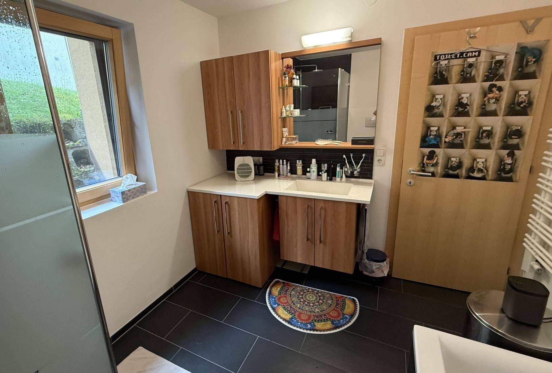 Modernes Badezimmer mit Holzwaschtisch, Spiegelschrank und Fenster für Tageslicht.