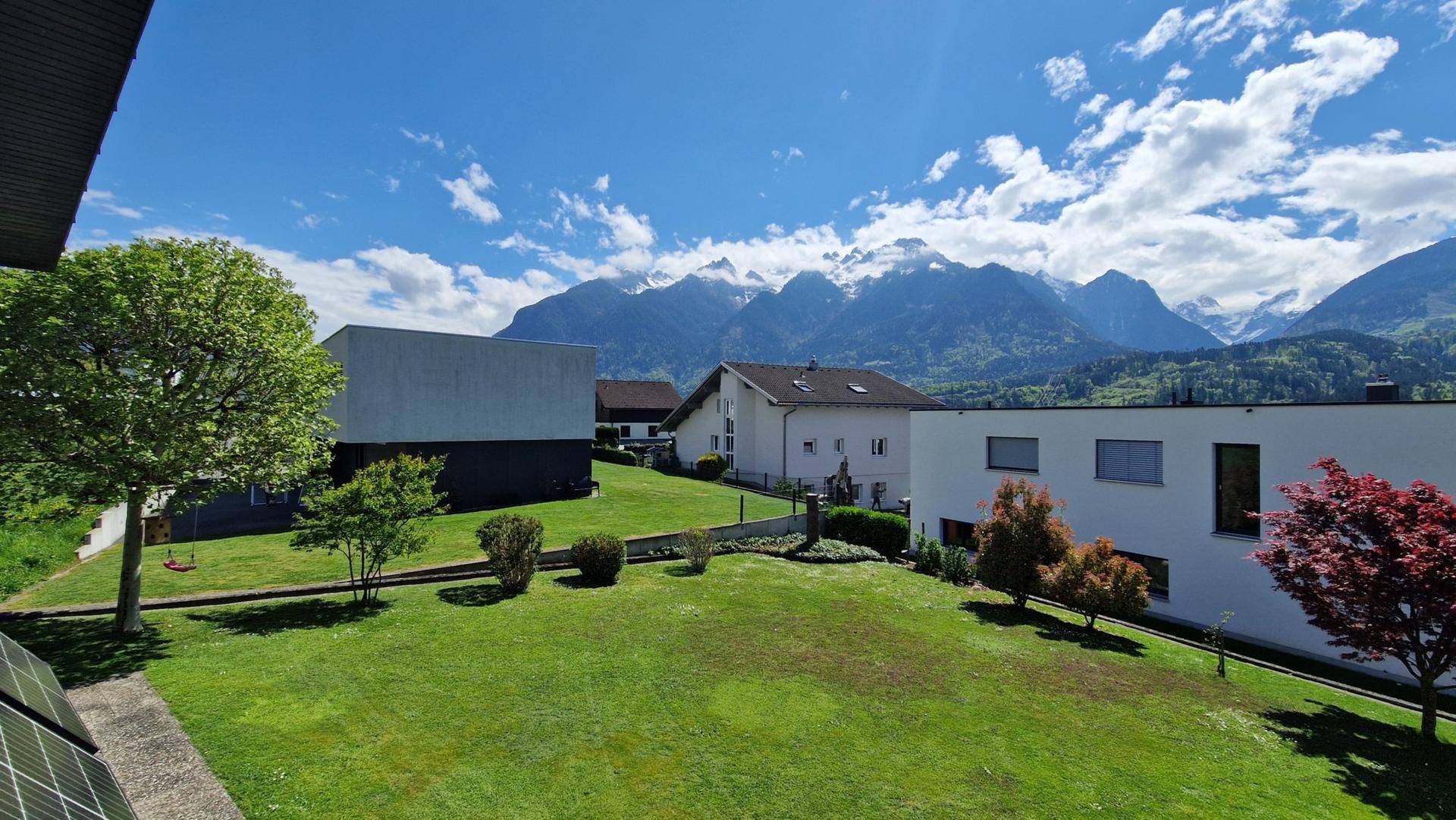 Weitläufiger Blick über die grüne Landschaft und die beeindruckenden Berge.