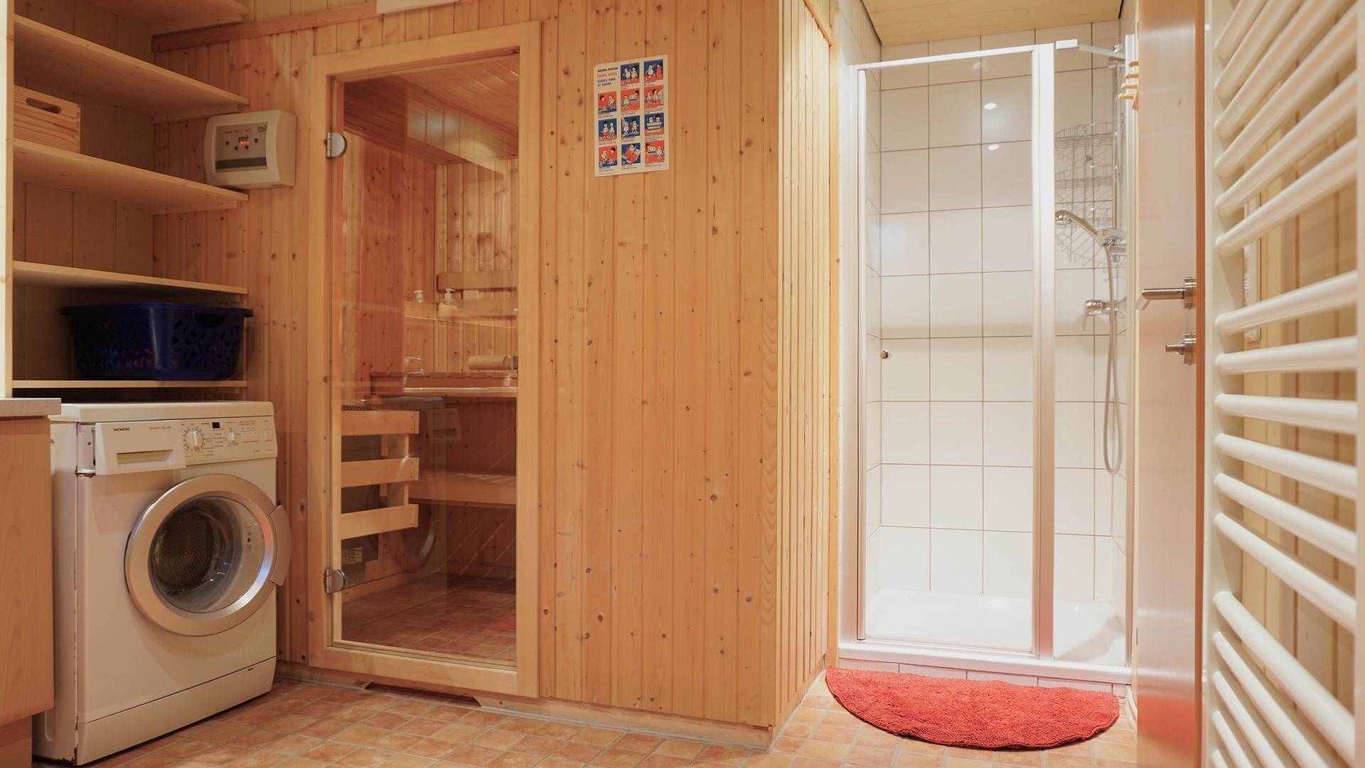 Badezimmer mit integrierter Sauna, Dusche und Waschmaschine für Komfort.