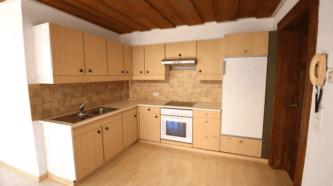 Helle Küche mit Holzdecken, Einbauschränken und integrierten Geräten in traditionellem Stil.