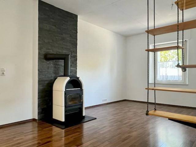 Gemütliches Wohnzimmer mit Holzboden, Kaminofen und moderner Wandgestaltung.