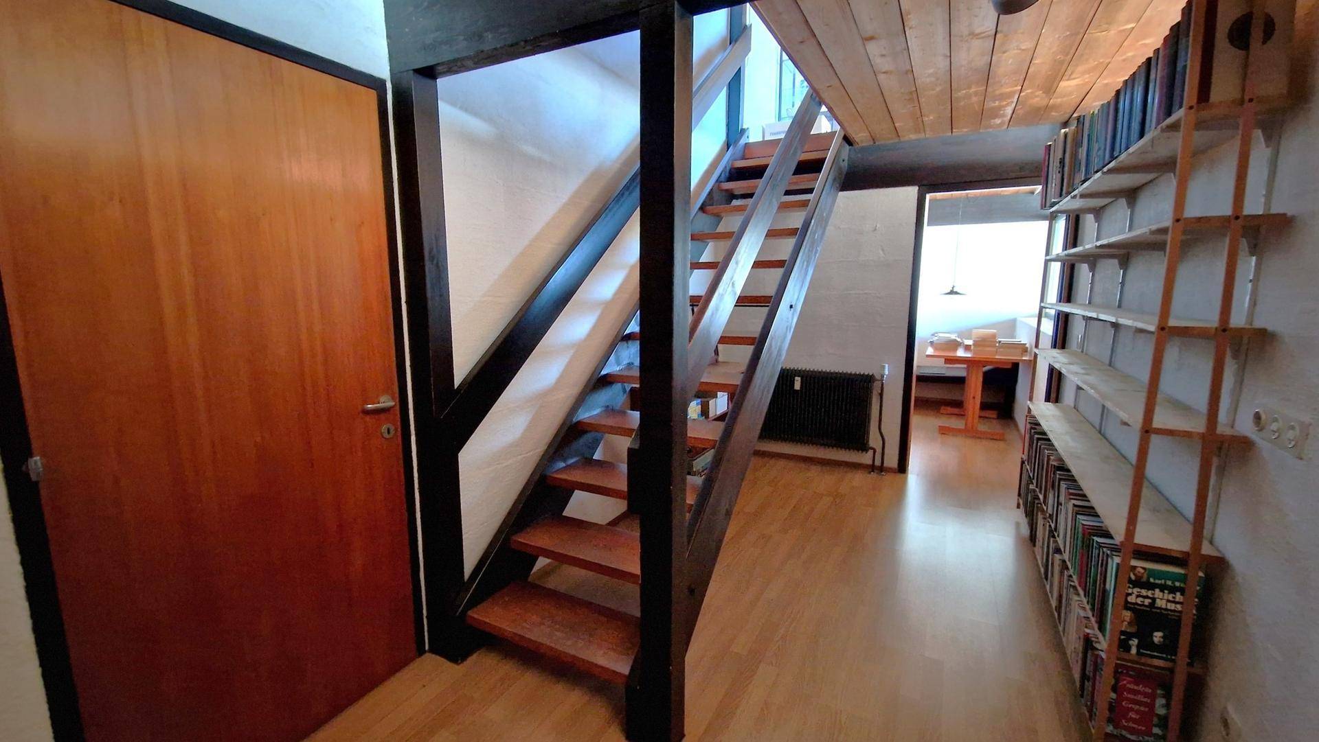 Heller Flur mit Holztreppe und Parkettboden, der zu weiteren Räumen führt.