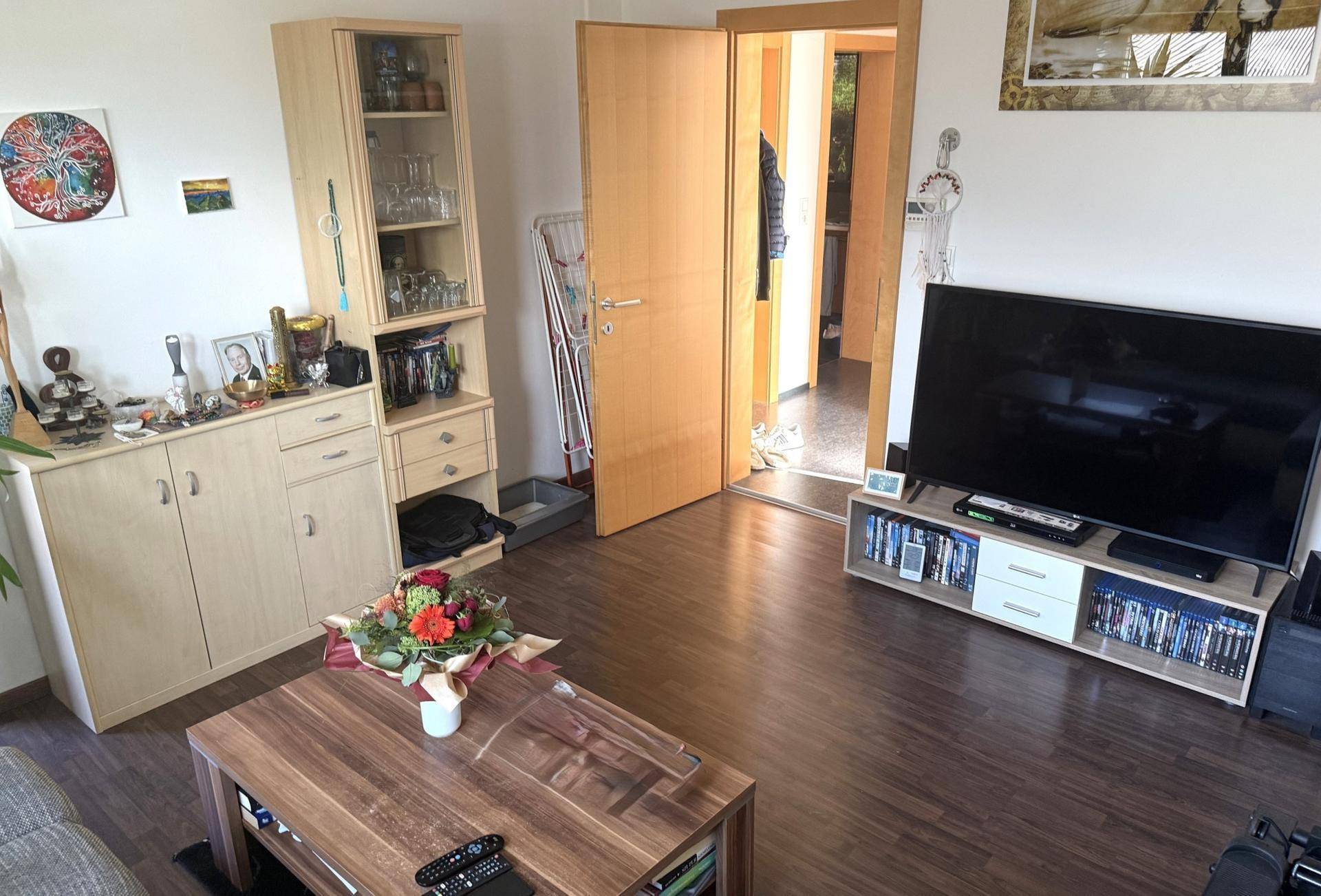 Gemütliches Wohnzimmer mit dunklem Laminatboden, TV-Möbel und Vitrinenschrank.