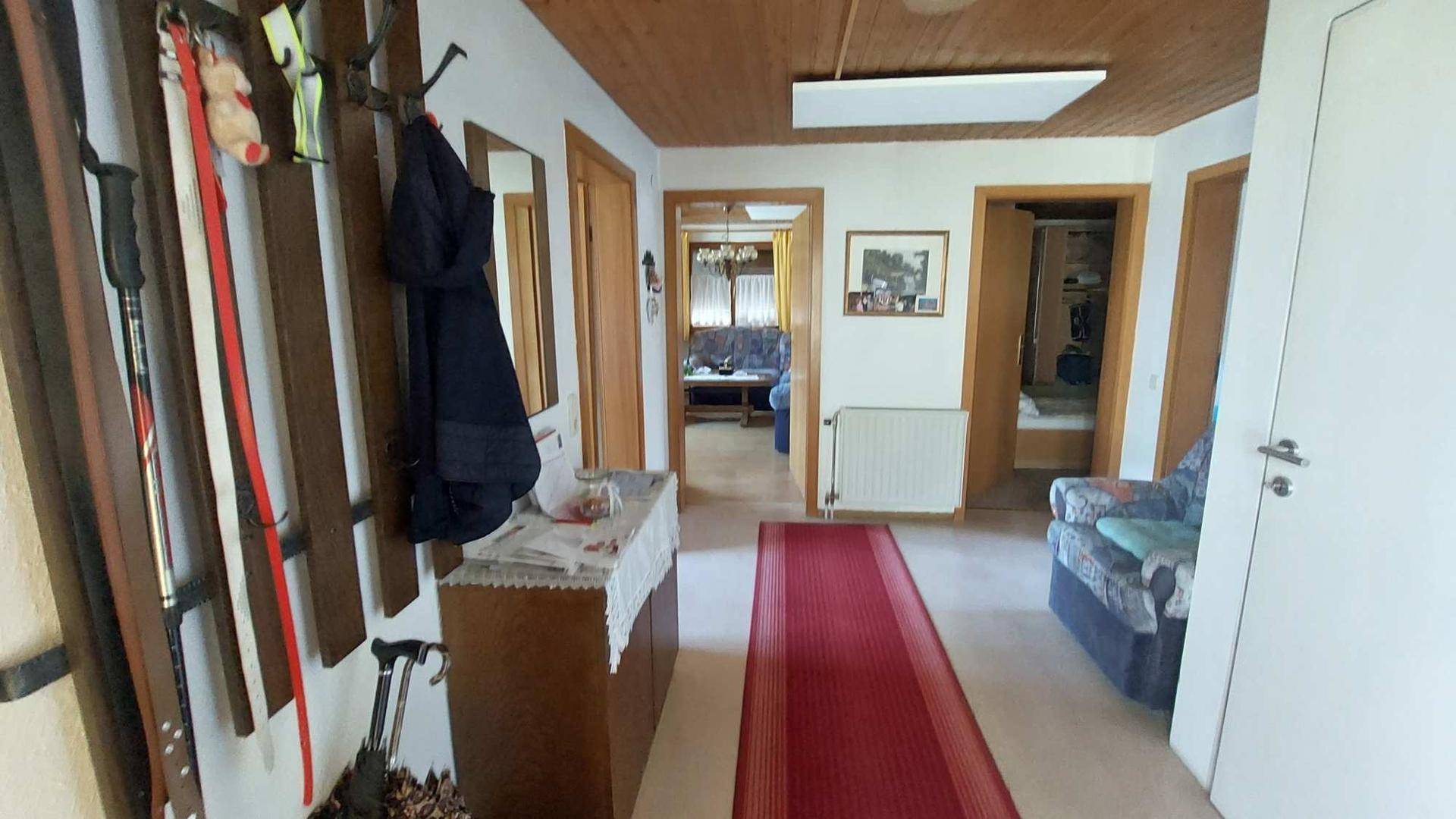 Gemütlicher Flur mit Holzdecke, Garderobe und Zugang zu verschiedenen Zimmern des Hauses.