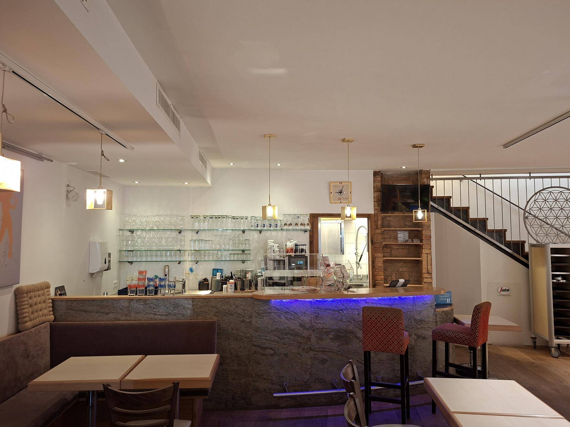 Moderner Barbereich mit Granit-Arbeitsplatte, Glasregalen und einer Treppe, die in eine obere Etage führt.