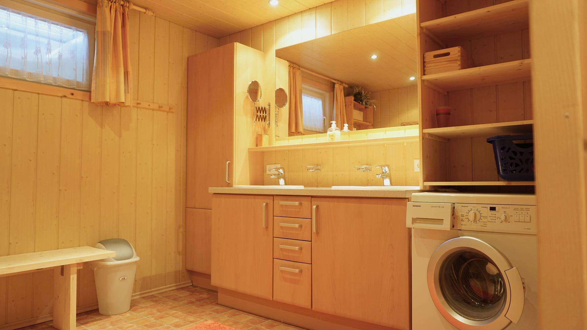Geräumiges Badezimmer mit Doppelwaschbecken, Waschmaschine und Holzvertäfelung.