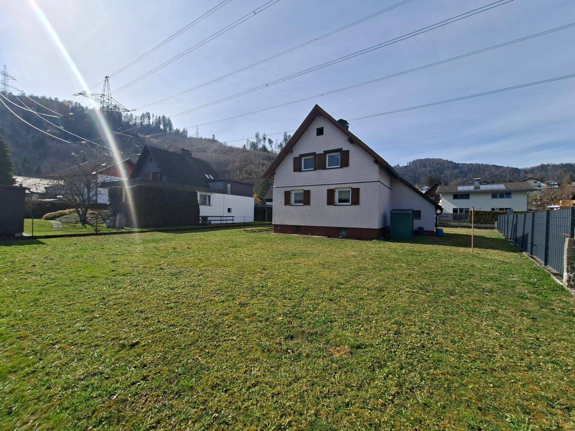 Rückansicht des Hauses mit weitläufigem Garten und Blick auf die umliegende Berglandschaft.