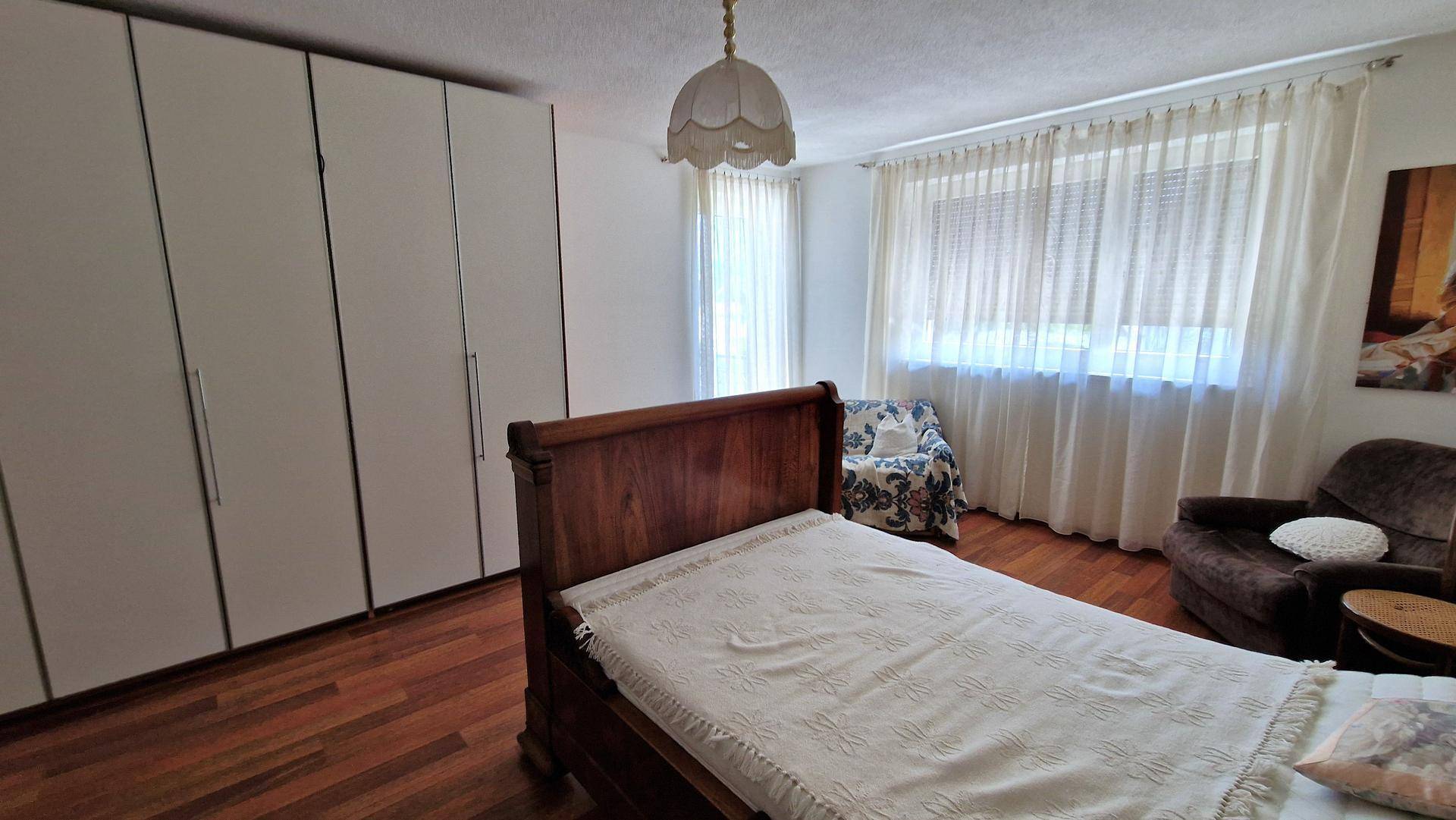 Schlafzimmer mit Holzboden, Einbauschränken und großen Fenstern für viel Tageslicht.