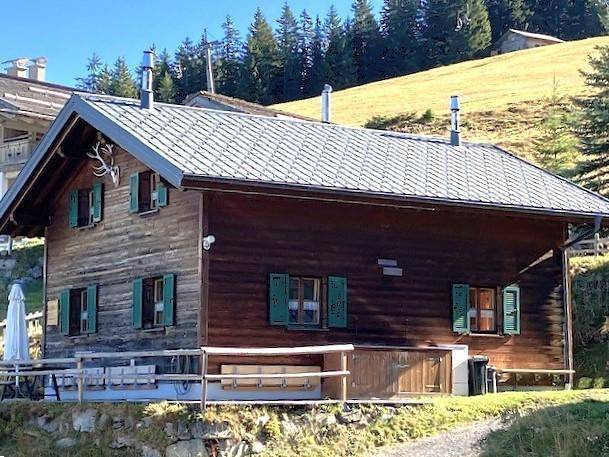 Rustikales Holzchalet mit Terrasse und Blick auf die umliegende Bergwelt.