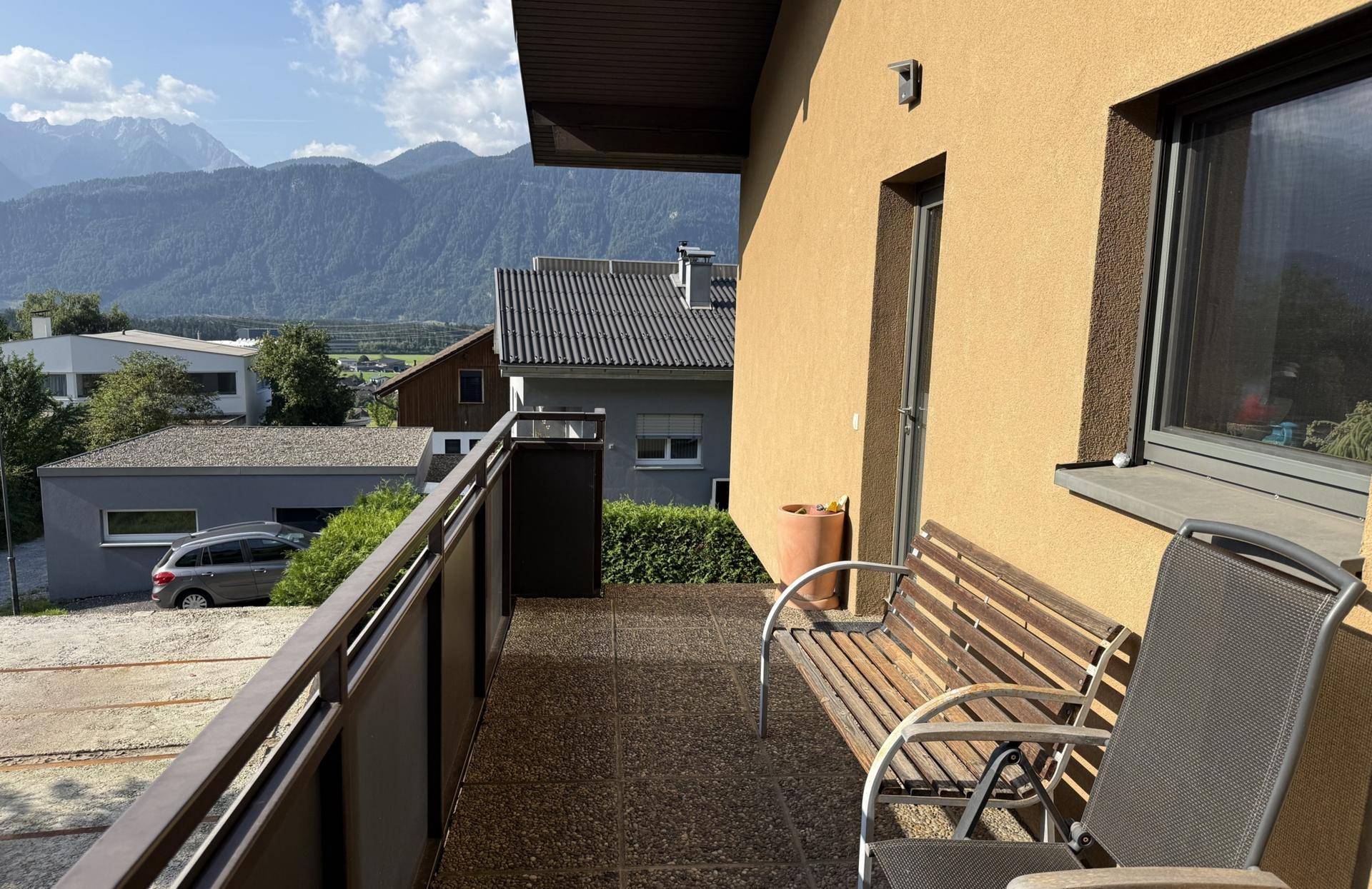 Balkon mit Sitzgelegenheiten und weitem Blick auf die Berge und die Umgebung.