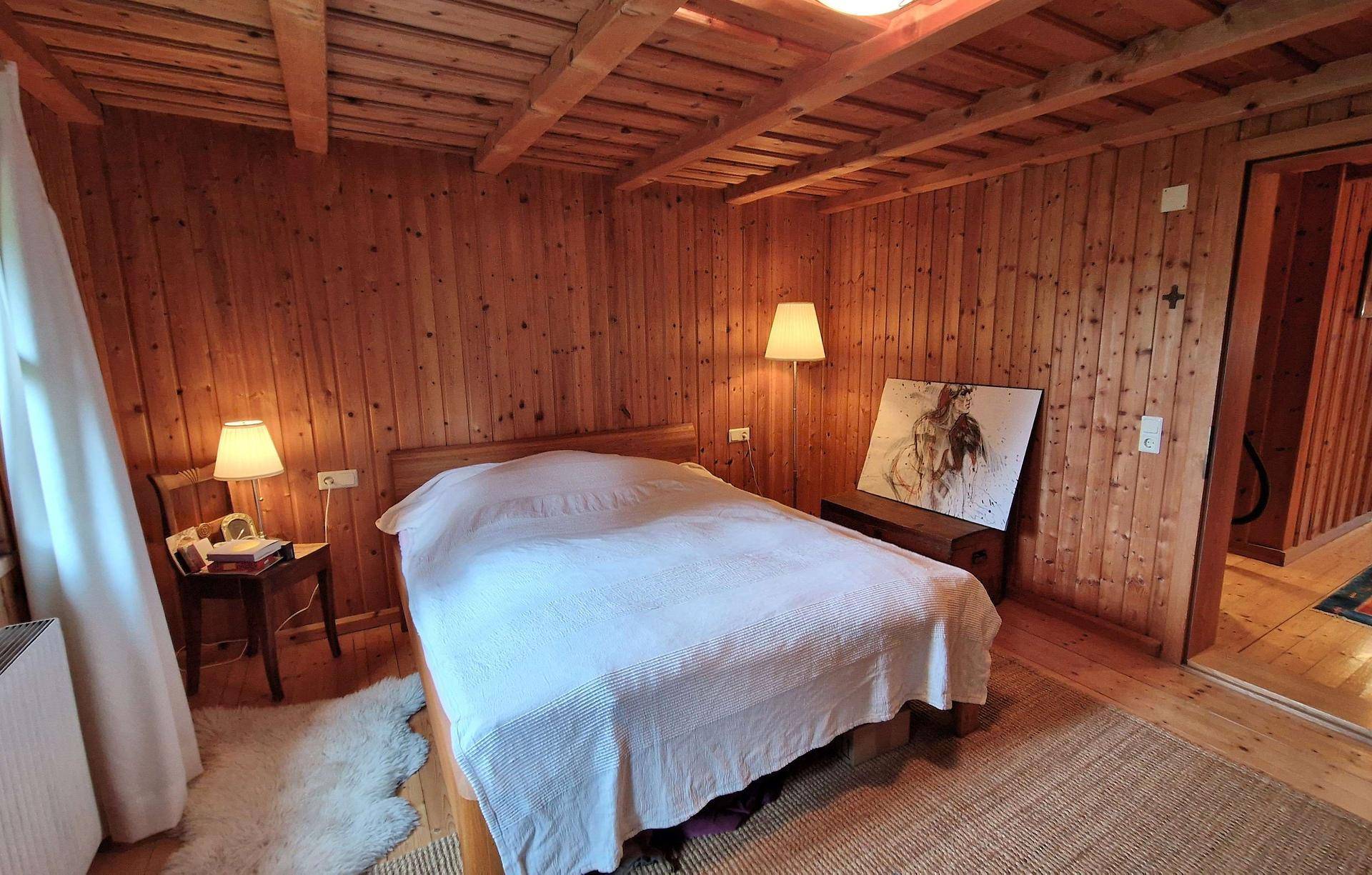 Schlafzimmer mit Holzboden, Holzvertäfelung, Doppelbett und Nachttischen.