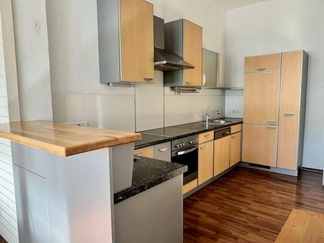 Funktionale Küche mit Holzfronten, dunkler Arbeitsplatte und integrierten Geräten.