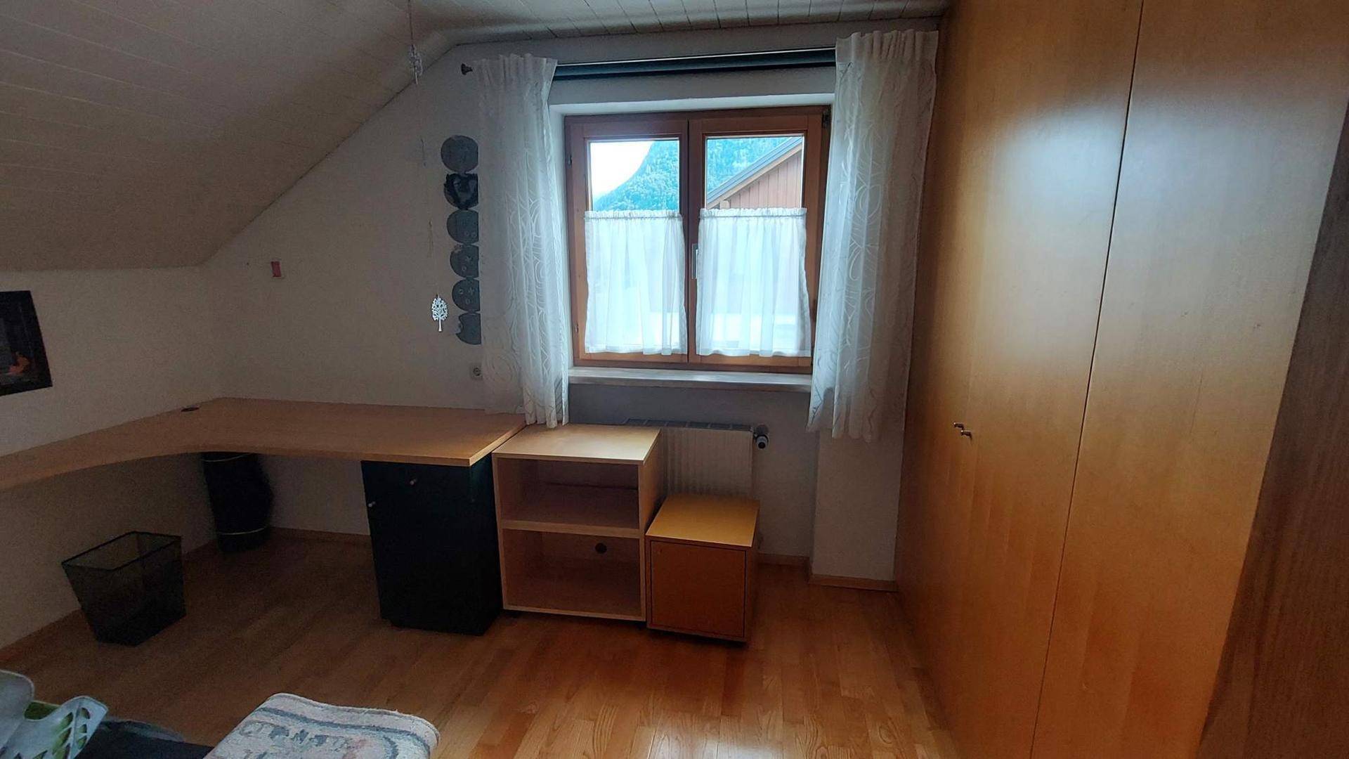 Arbeitszimmer im Dachgeschoss mit Schreibtisch, Holzboden und Fenster mit Blick ins Grüne.