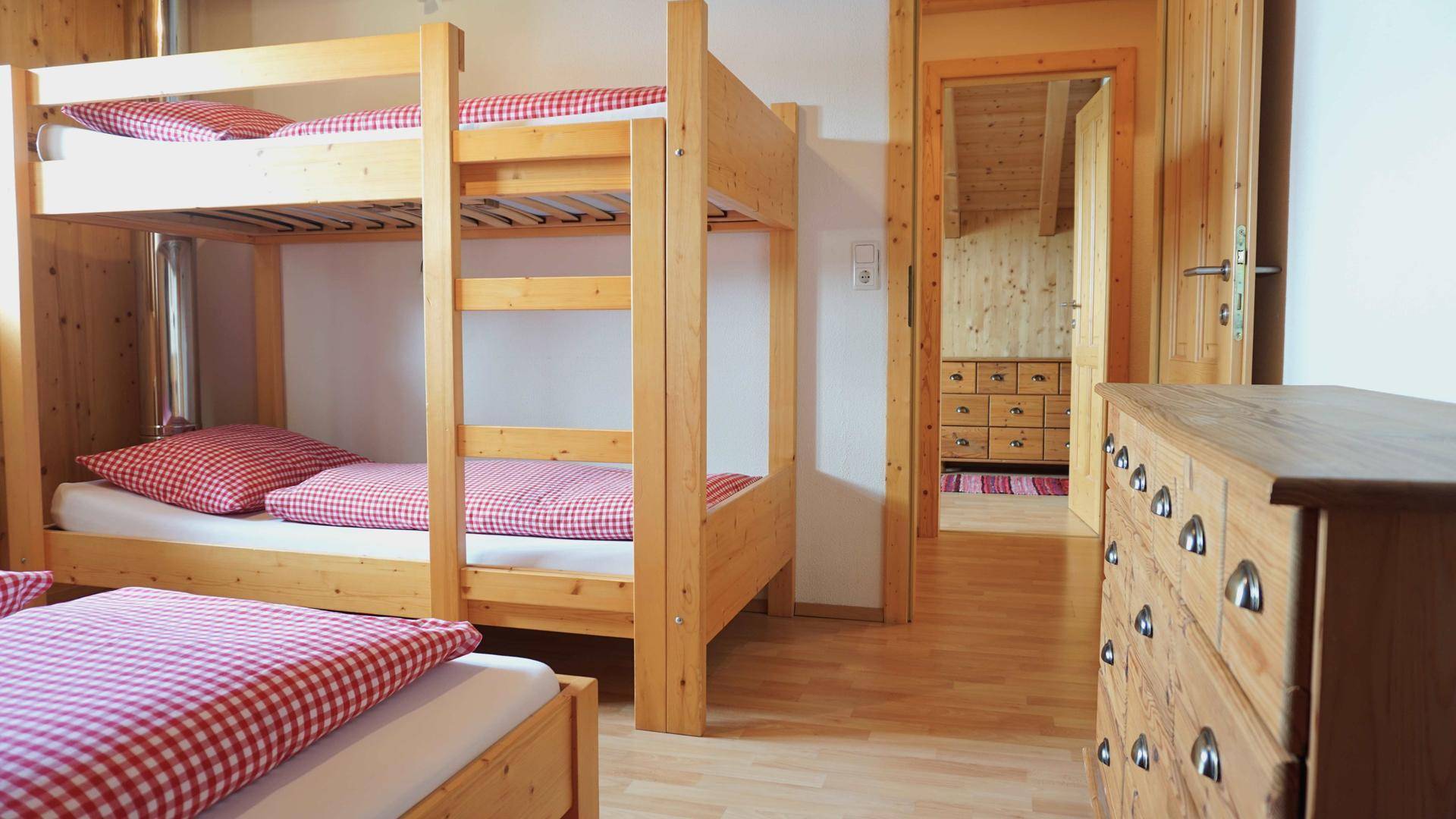 Rustikales Schlafzimmer mit Etagenbetten und Holzkommode, ideal für Familien.