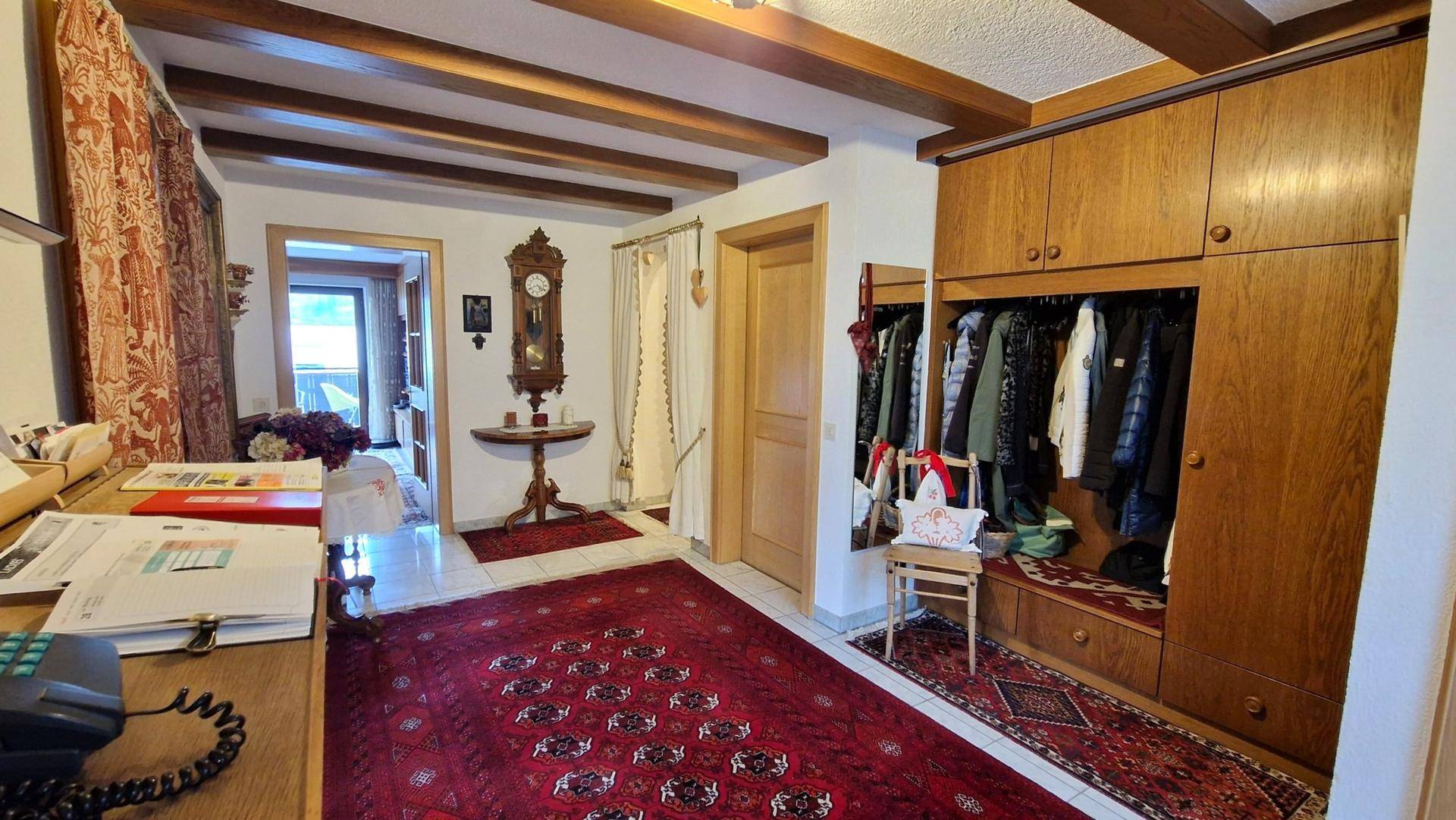 Geräumiger Flur mit Holzbalkendecke, Einbauschränken und traditionellem Teppichboden.