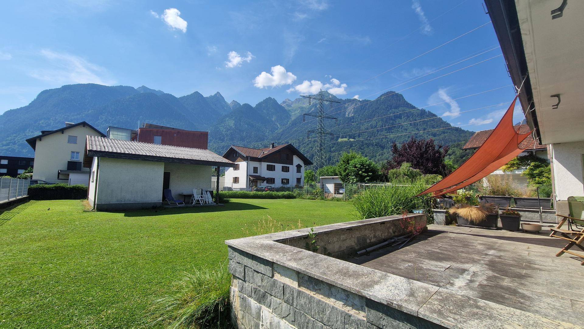 Große Steinterrasse mit Sitzgelegenheiten und beeindruckendem Bergblick unter blauem Himmel.