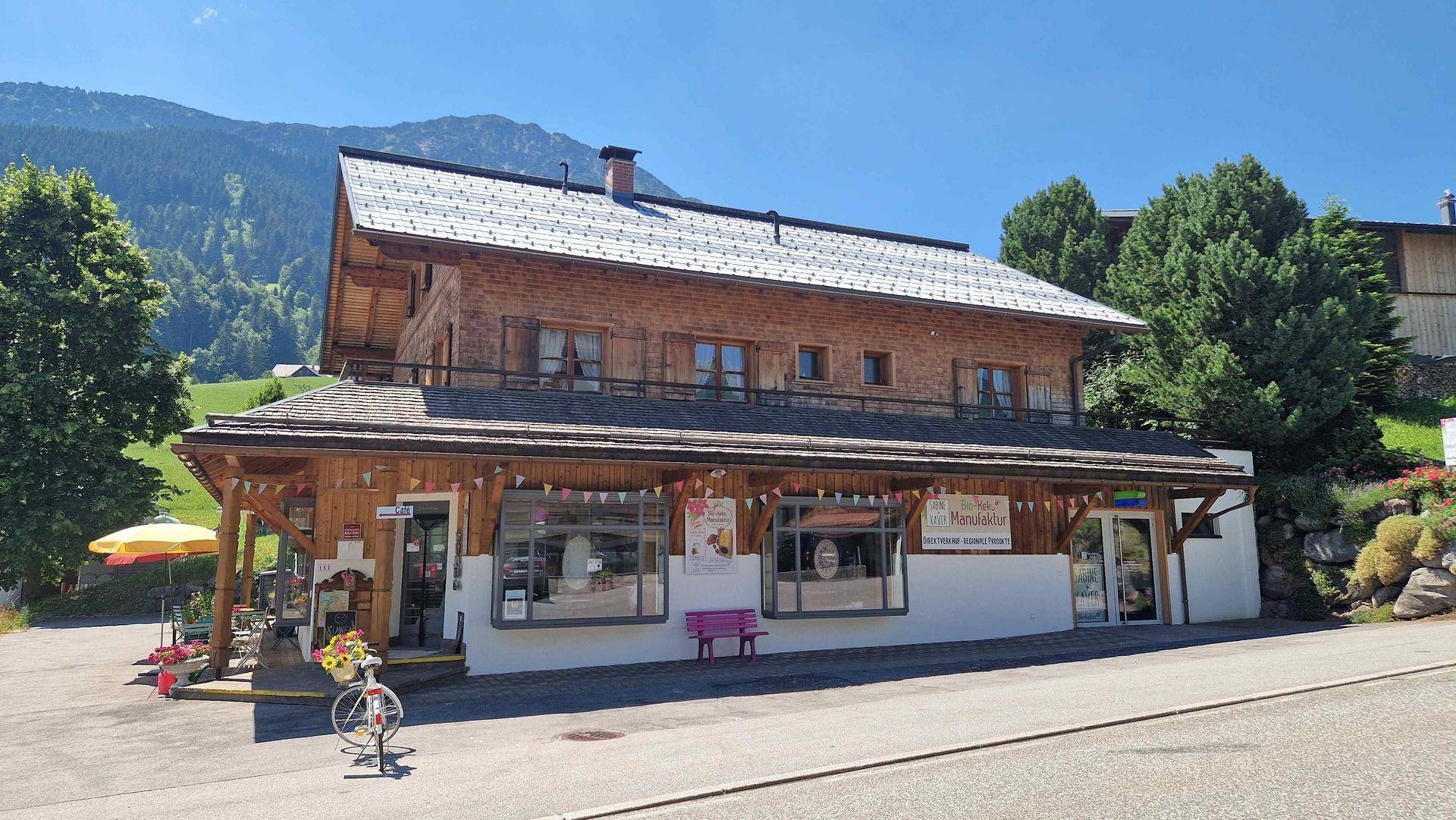 Charmantes Holzhaus im Alpenstil mit Geschäften im Erdgeschoss und Bergkulisse.