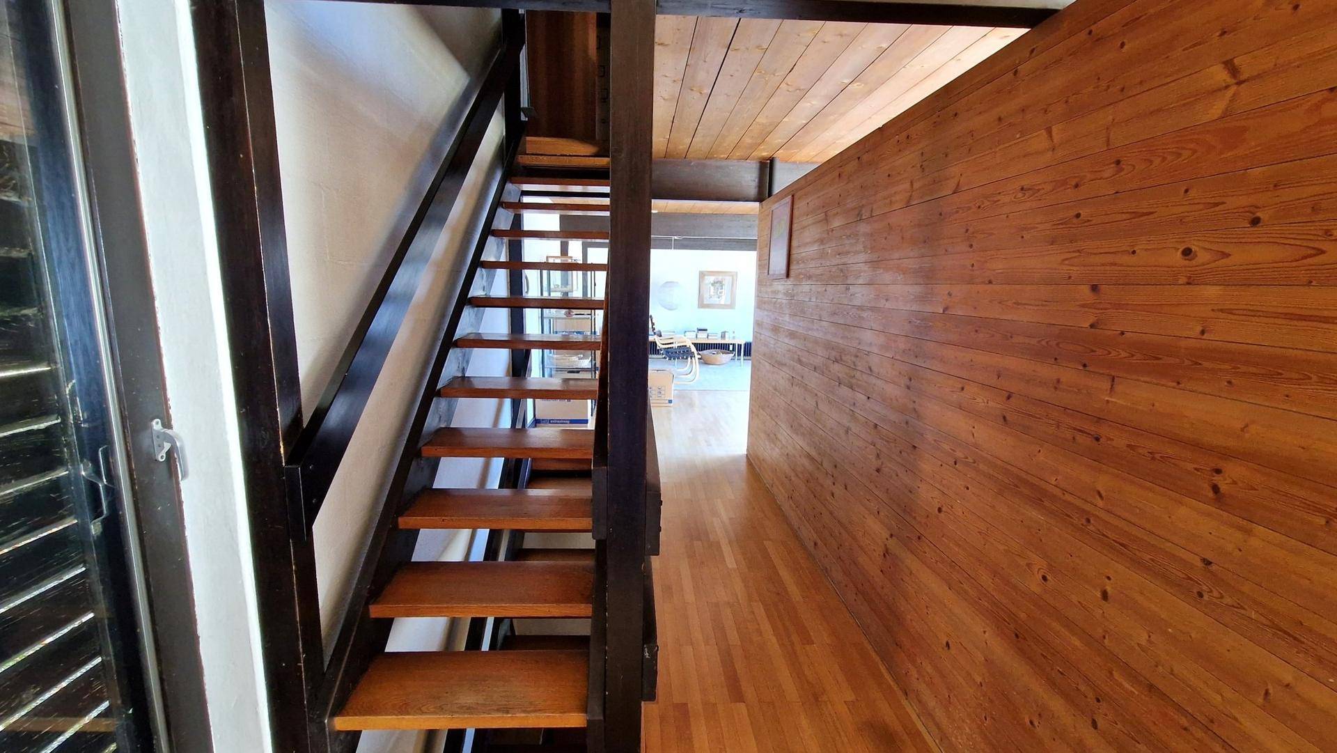 Geräumiger Flur mit Holztreppe, Holzwänden und Parkettboden, der die Ebenen verbindet.