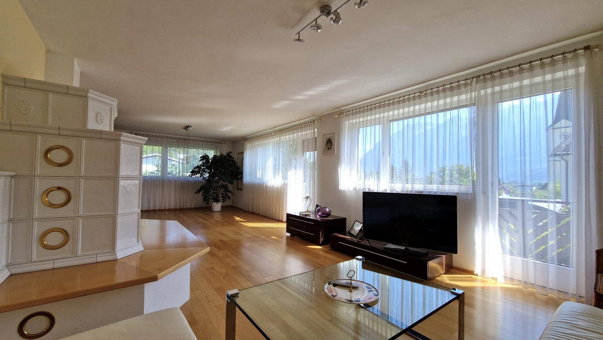 Helles Wohnzimmer mit Parkettboden, großzügigen Fenstern und Blick auf die Umgebung.