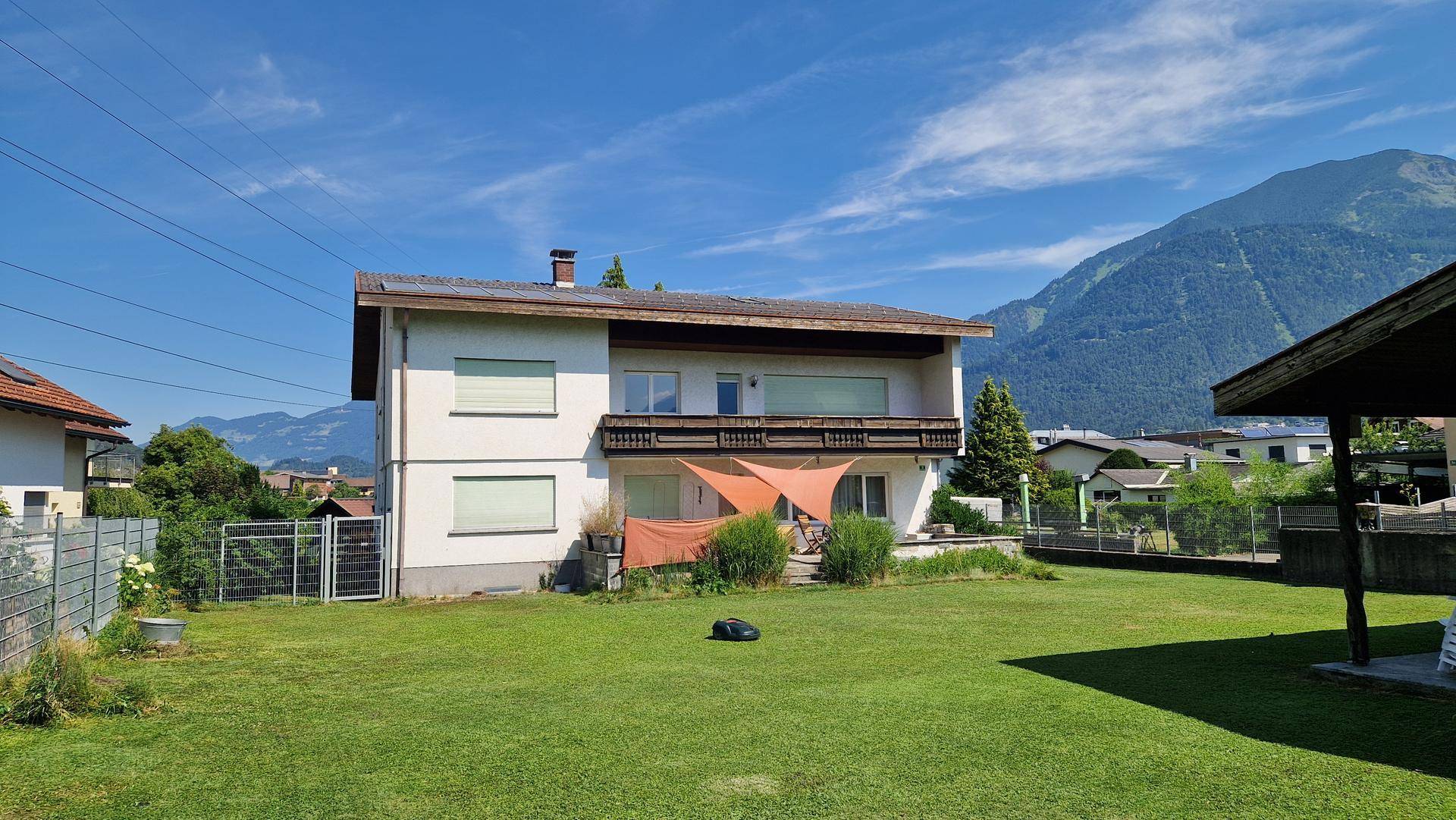 Weitläufiger Gartenbereich mit Rasenfläche und freiem Blick auf die umliegenden Berge.