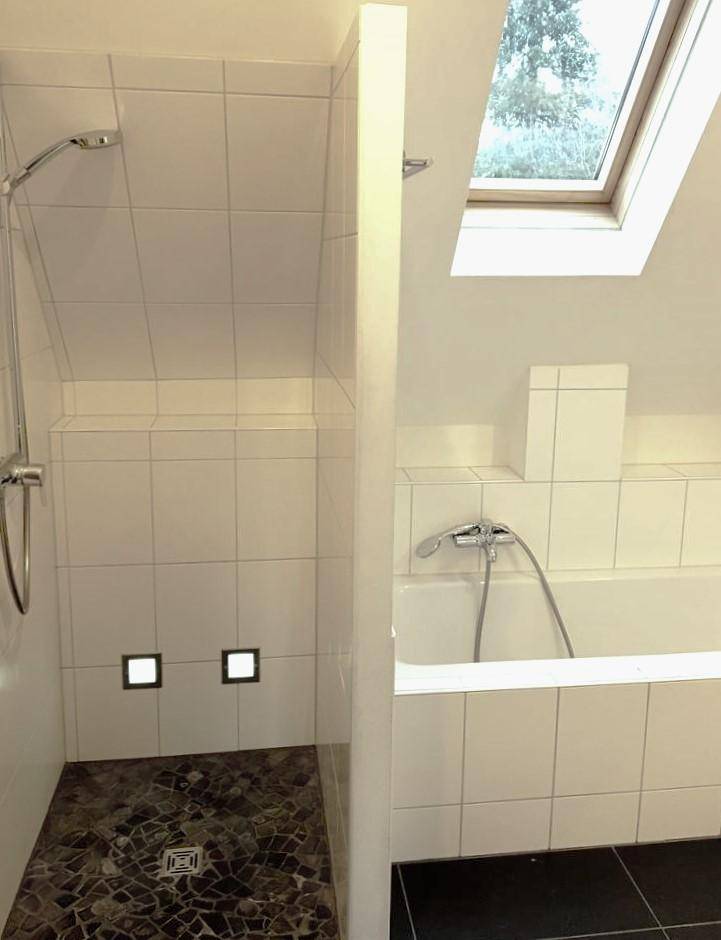 Helles Badezimmer im Dachgeschoss mit Dusche, Badewanne und Dachfenster.