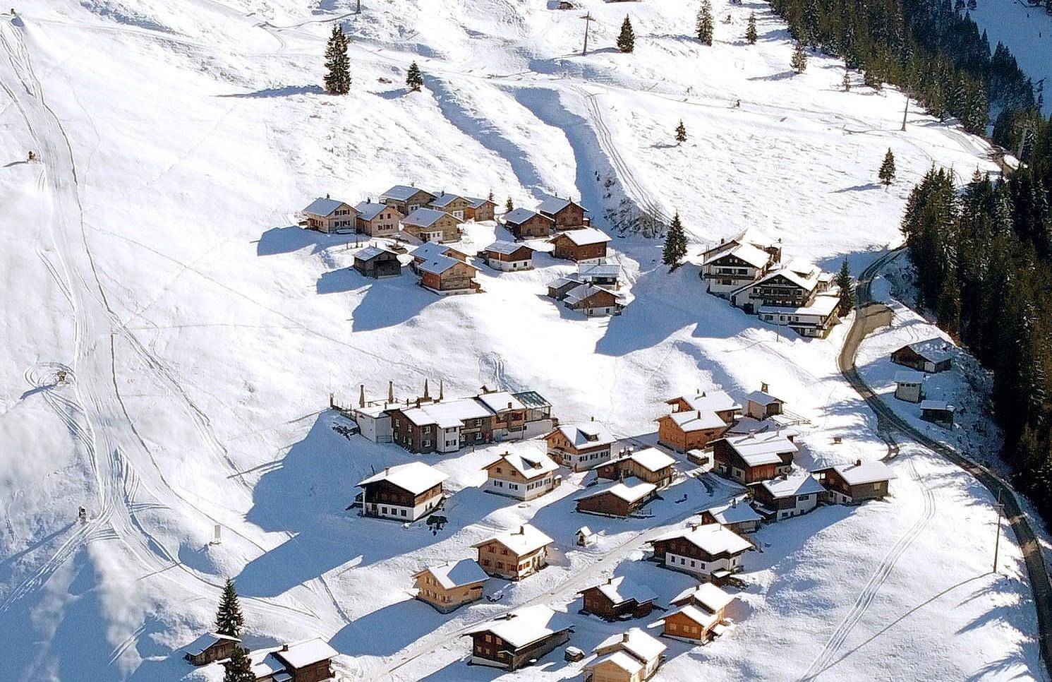 Vogelperspektive eines weitläufigen Skigebiets mit zahlreichen Hütten und Pisten.