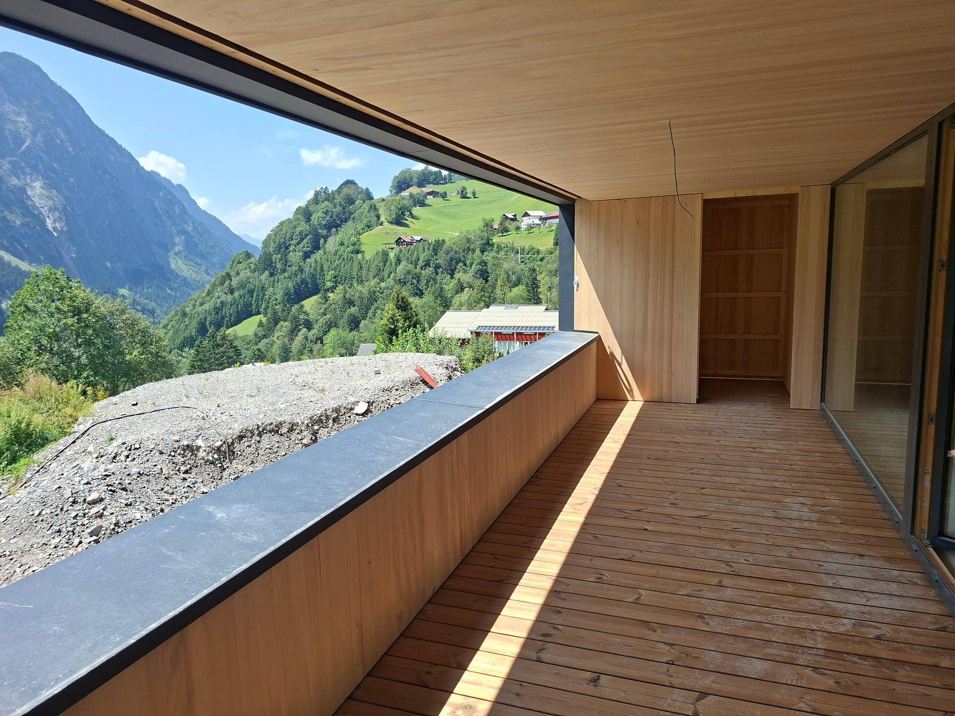 Geräumige Loggia mit Holzboden und atemberaubendem Blick auf die umliegende Berglandschaft.