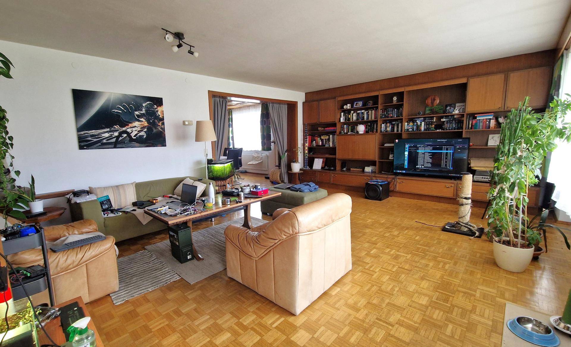 Gemütliches Wohnzimmer mit Parkettboden, Holzwandregal und bequemen Sofas.