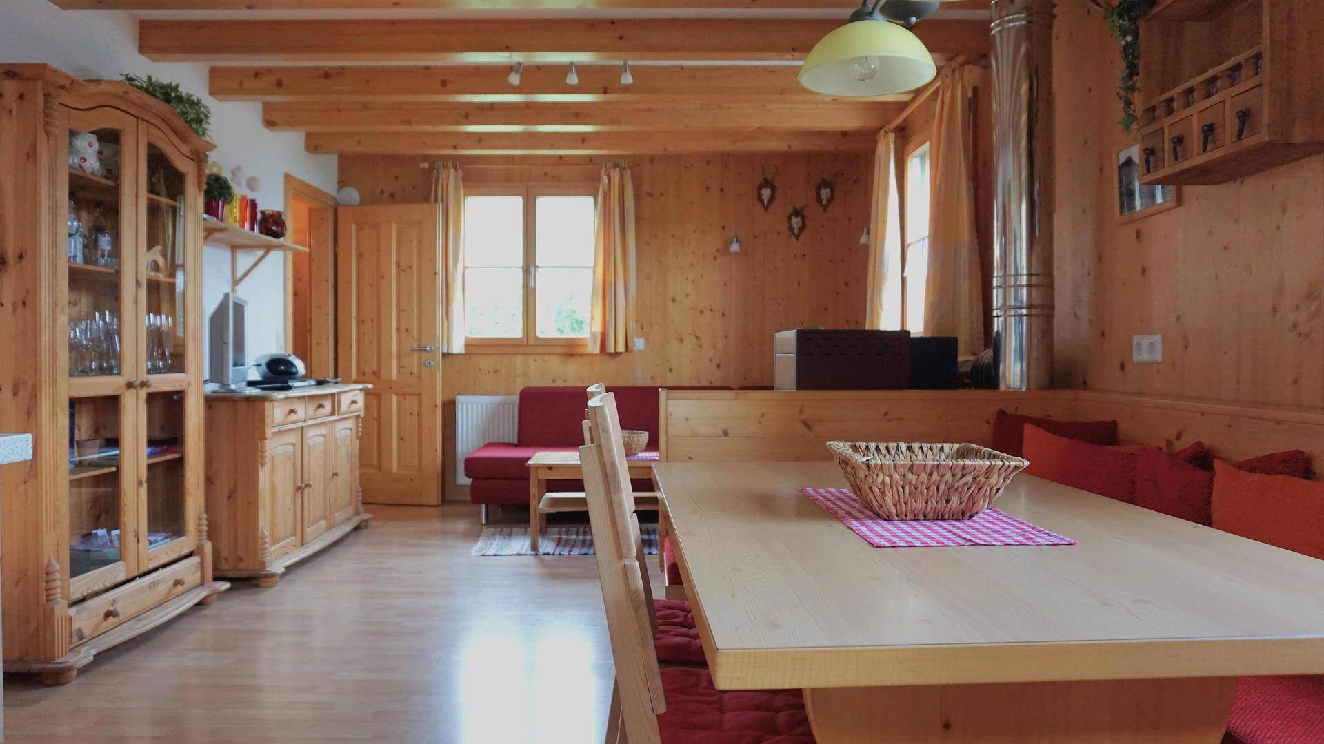 Gemütlicher Wohn-Essbereich im alpinen Stil mit Holzvertäfelung und traditionellen Möbeln.