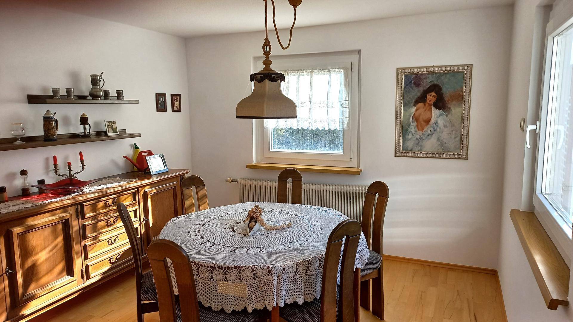 Gemütliches Esszimmer mit traditionellen Holzmöbeln und einem Fenster mit Gardinen.