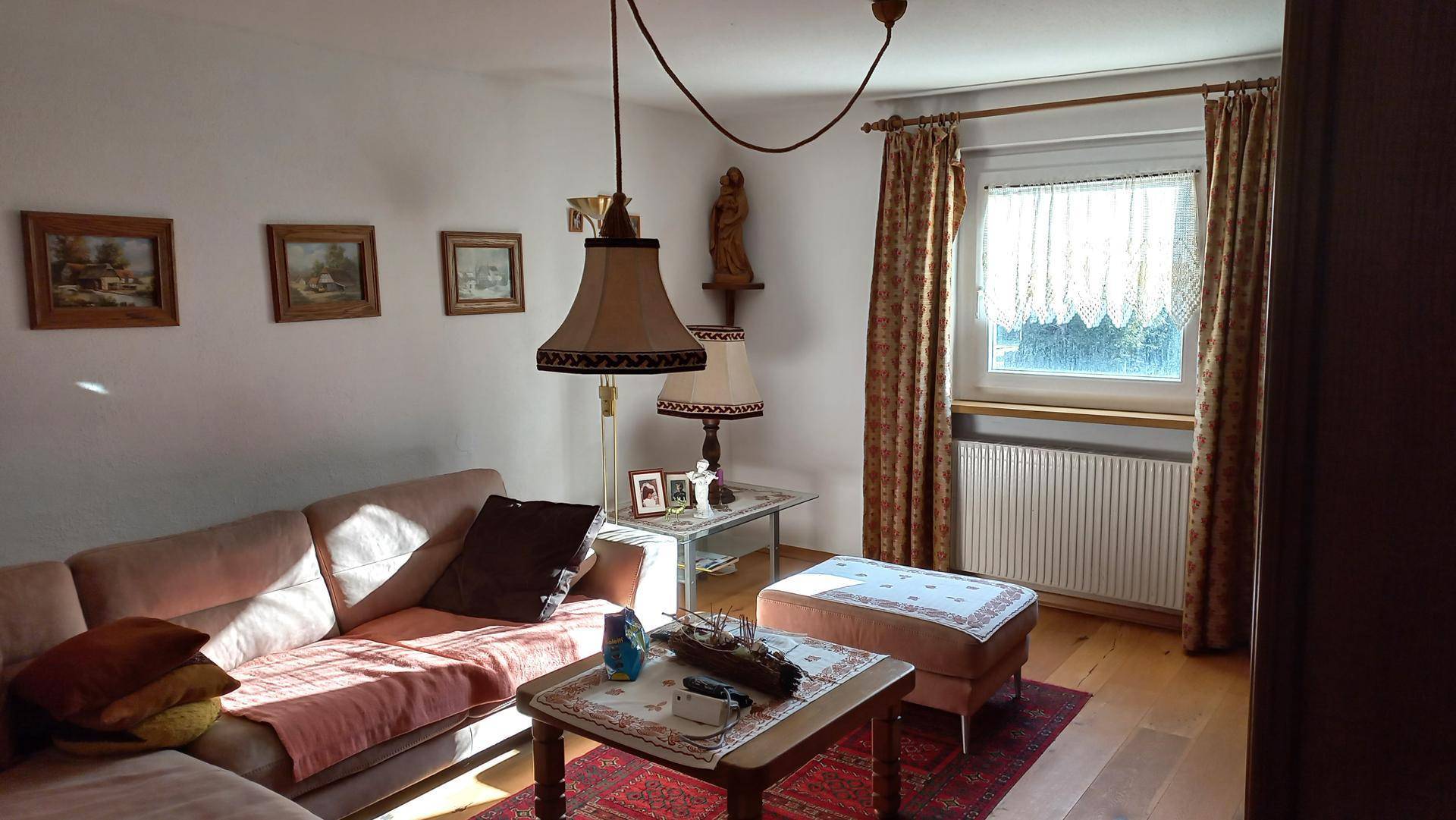 Gemütliches Wohnzimmer mit beigem Sofa, Holzboden und traditioneller Einrichtung.