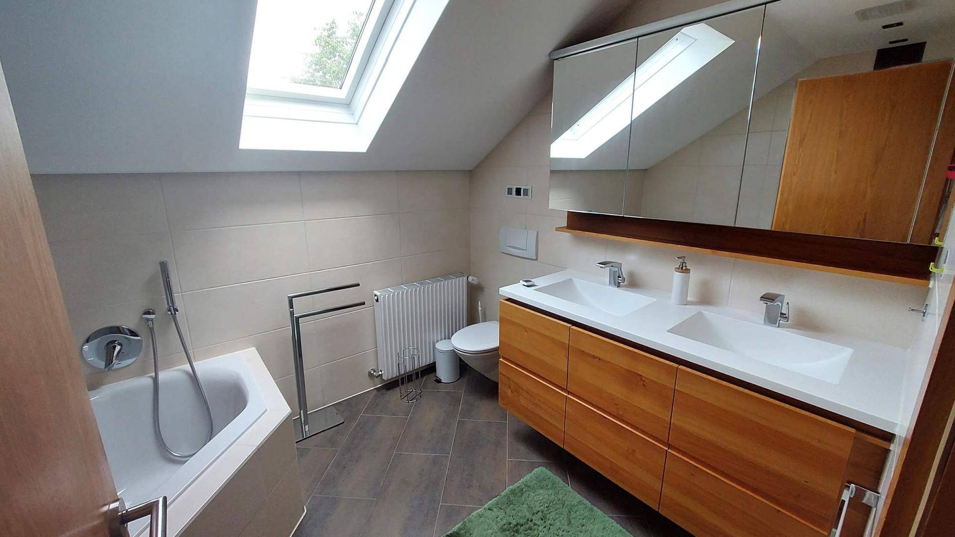 Modernes Badezimmer im Dachgeschoss mit Doppelwaschbecken, Eckbadewanne und Dachfenster.