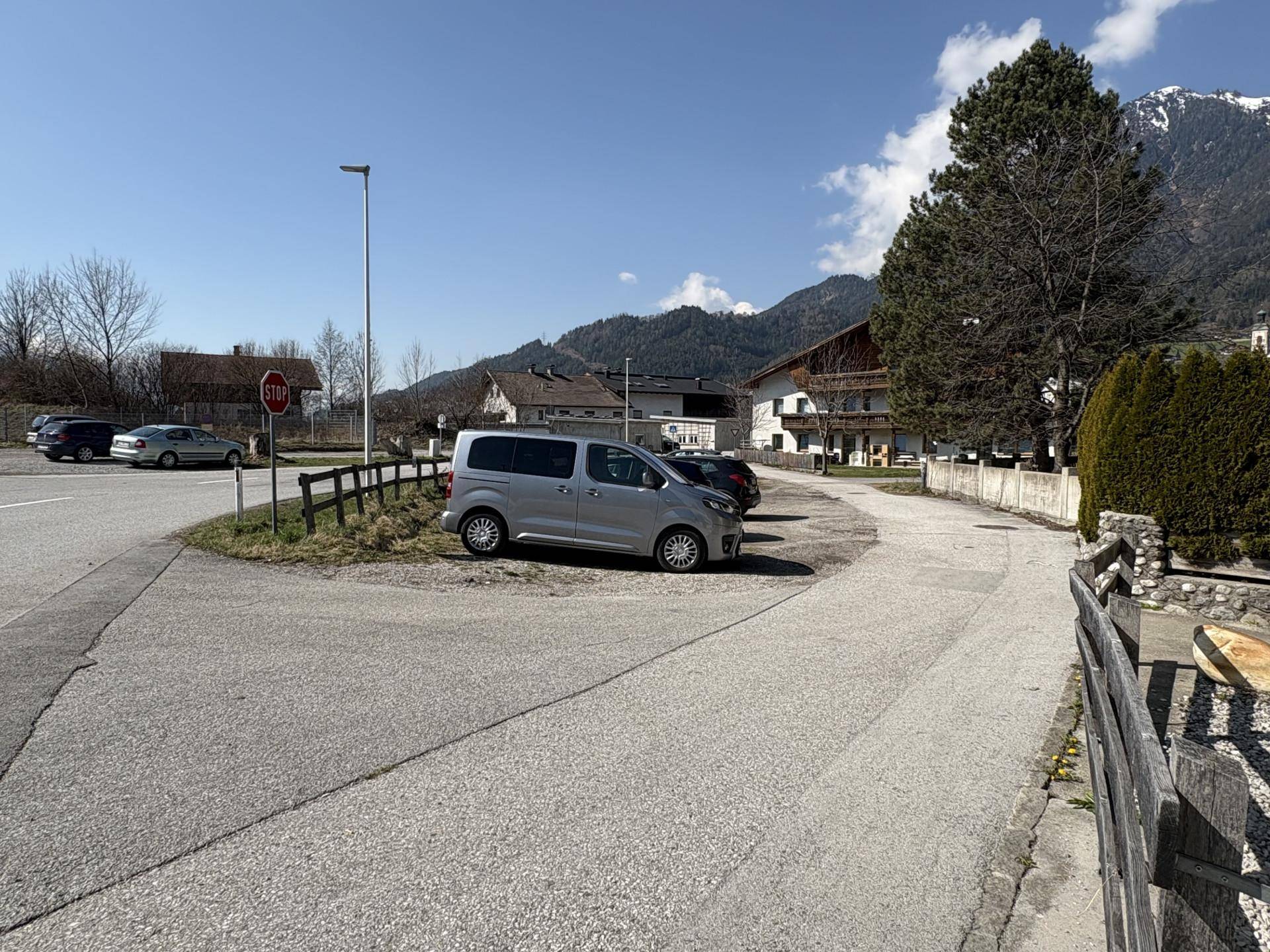 Außenparkplatz mit mehreren Fahrzeugen und Blick auf die umliegenden Berge.