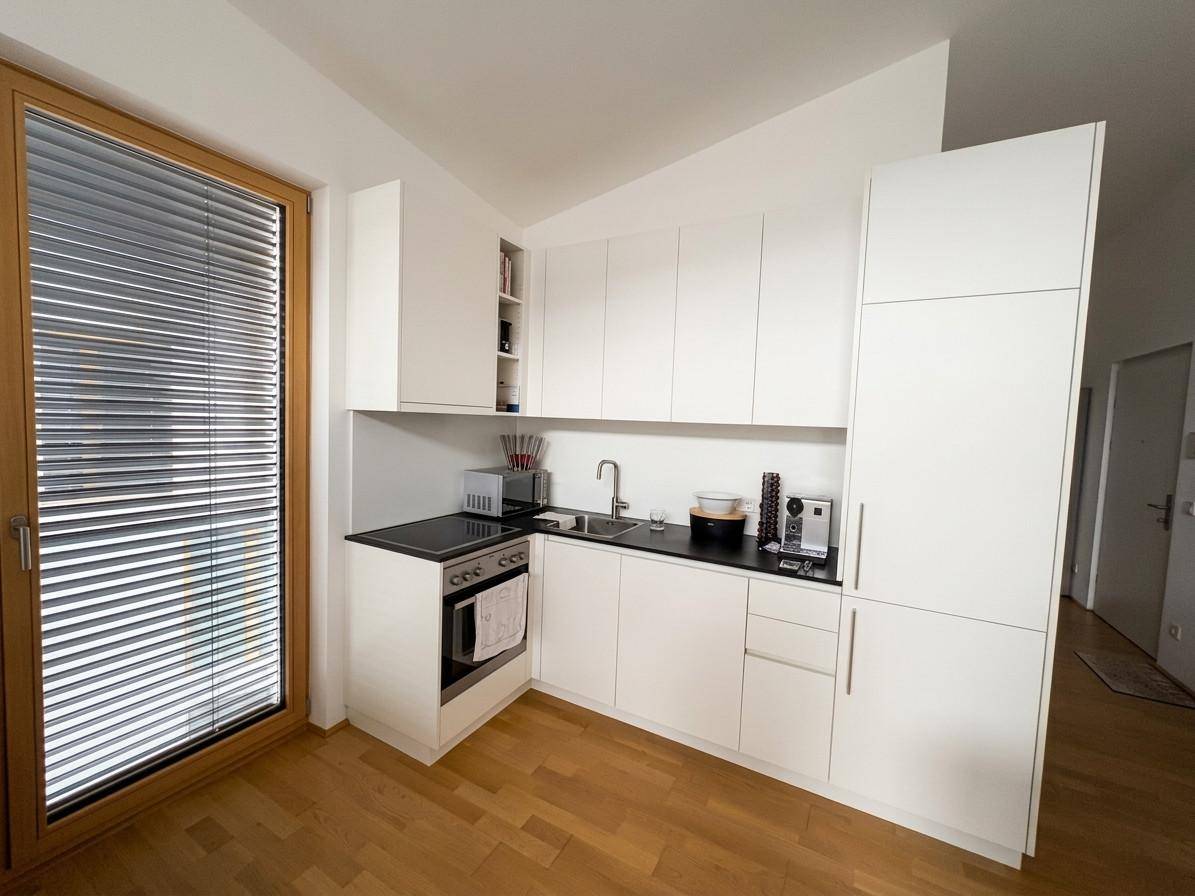 Moderne, weiße Einbauküche mit minimalistischem Design und integrierten Geräten.