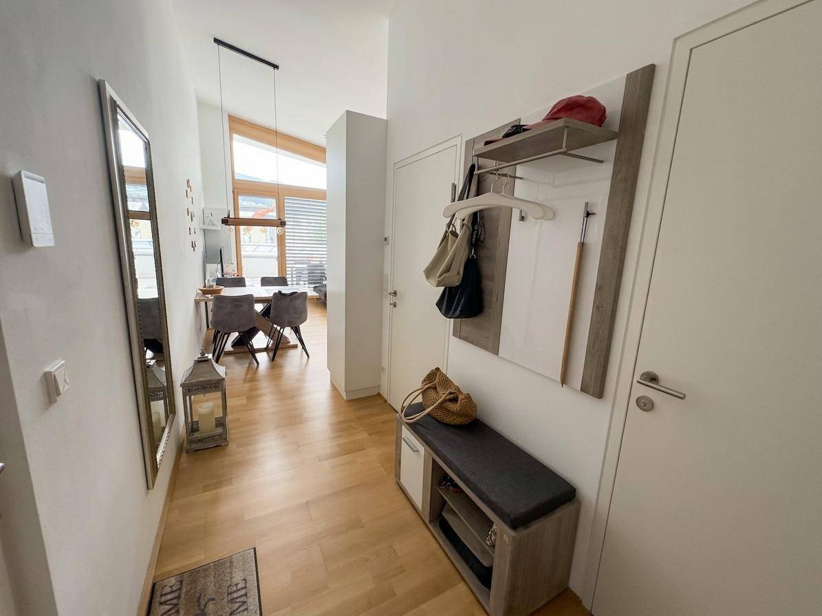 Heller Flur mit Garderobe, Spiegel und Holzboden, der zu den Wohnbereichen führt.