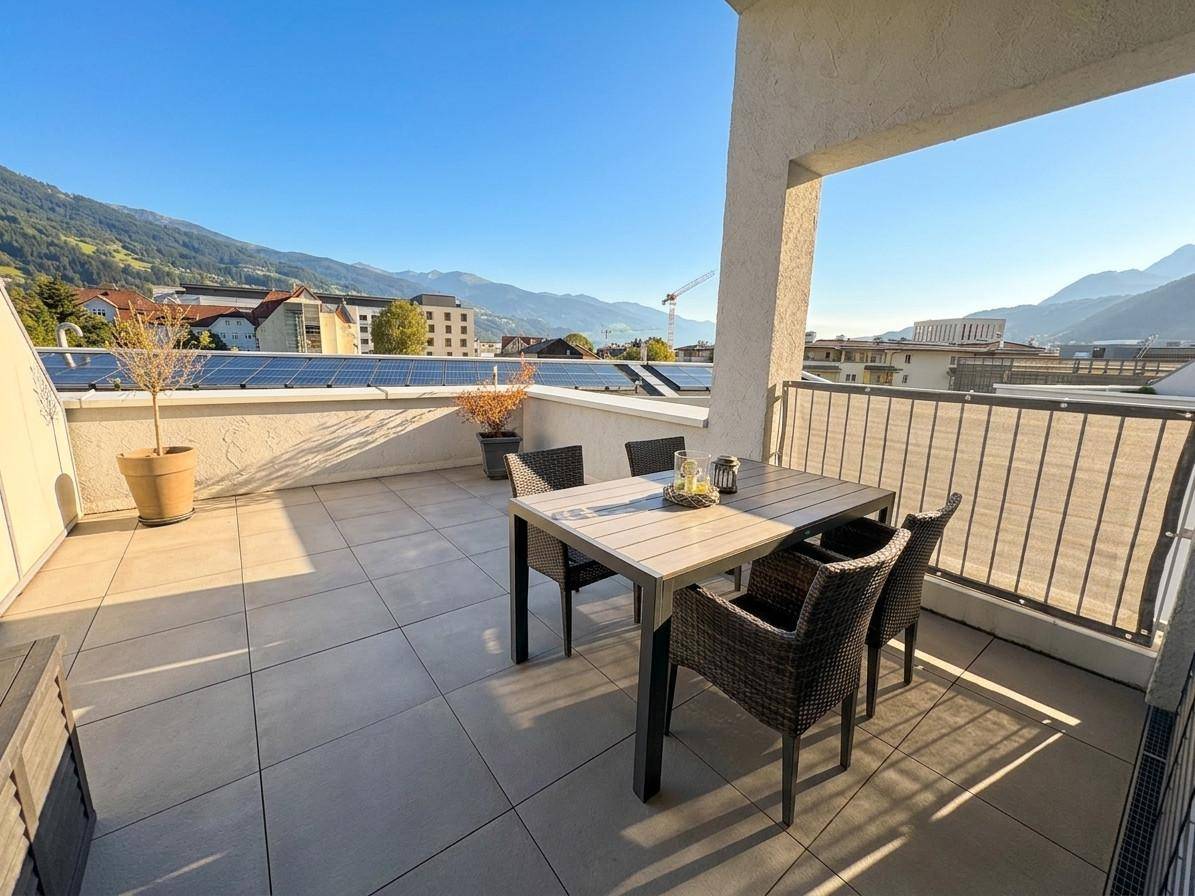 Sonnige Terrasse mit Essbereich und weitem Blick auf die umliegende Berglandschaft.