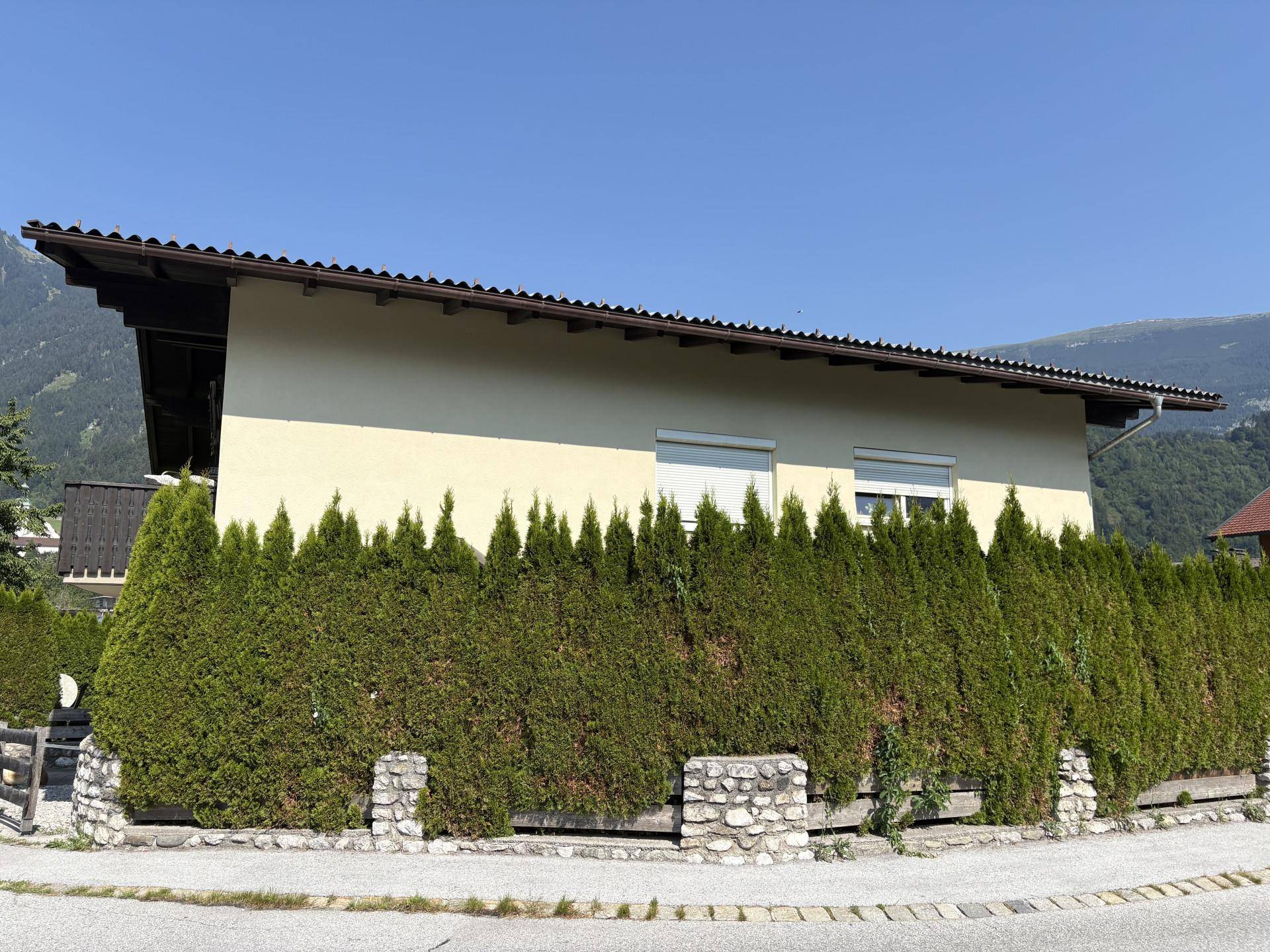 Vorderansicht des Hauses, geschützt durch eine hohe, dichte Hecke.