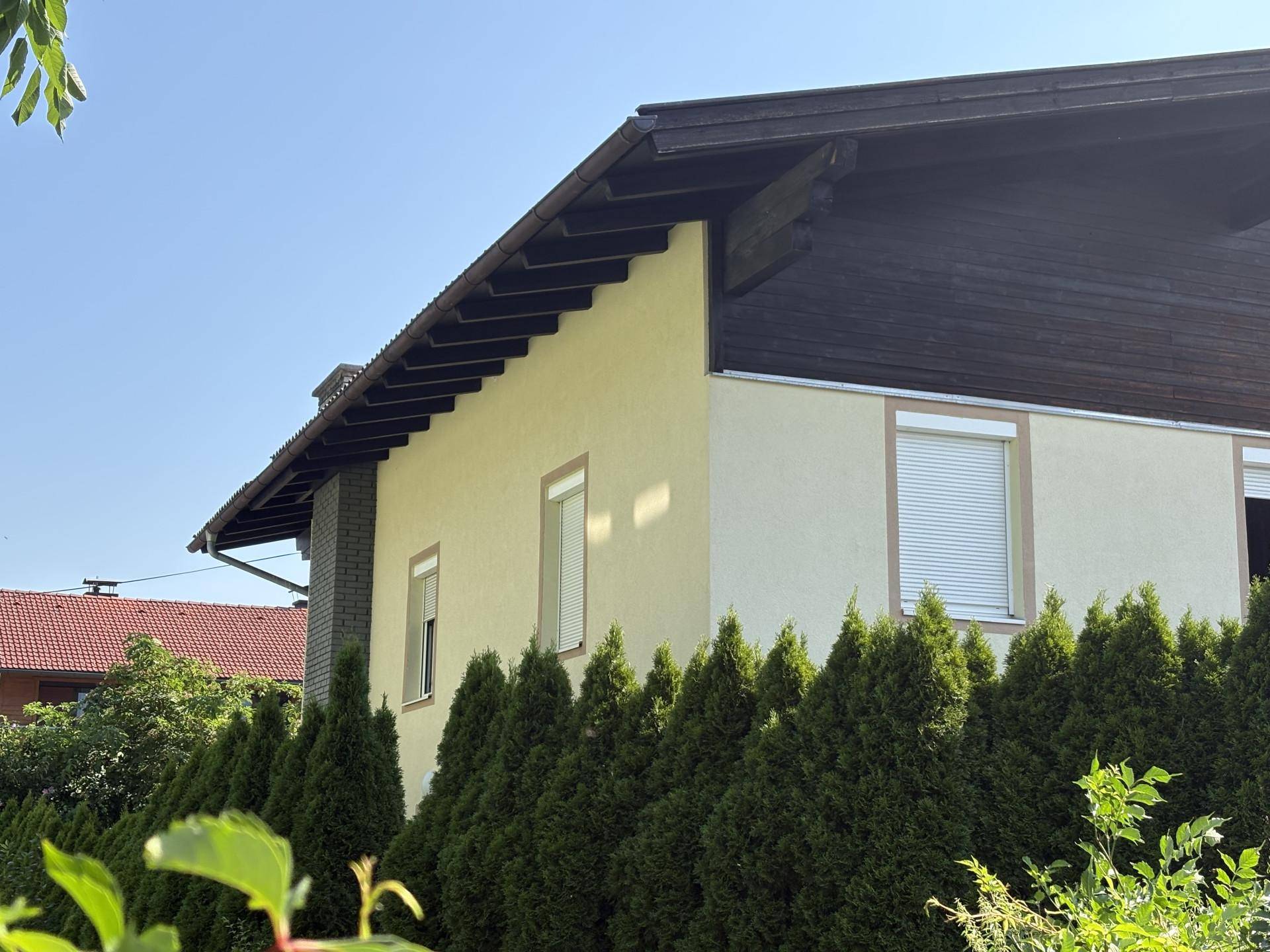 Eckansicht des Hauses mit Schornstein und Rollläden an den Fenstern.